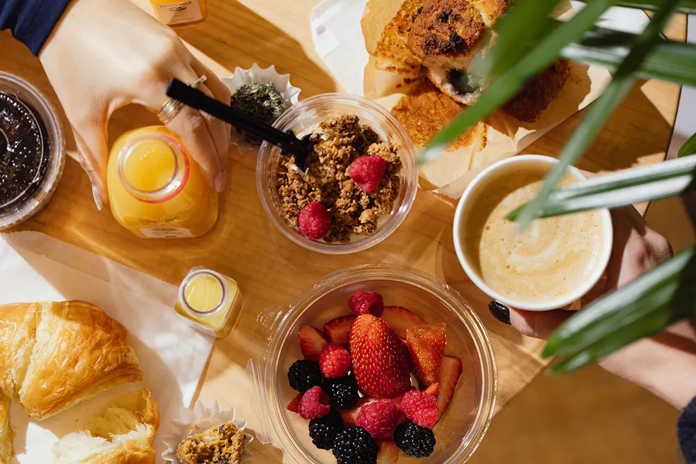 Breakfast spread at Boston Financial District food hall The Lineup with coffee, pastries, fresh fruit, granola, and juice.