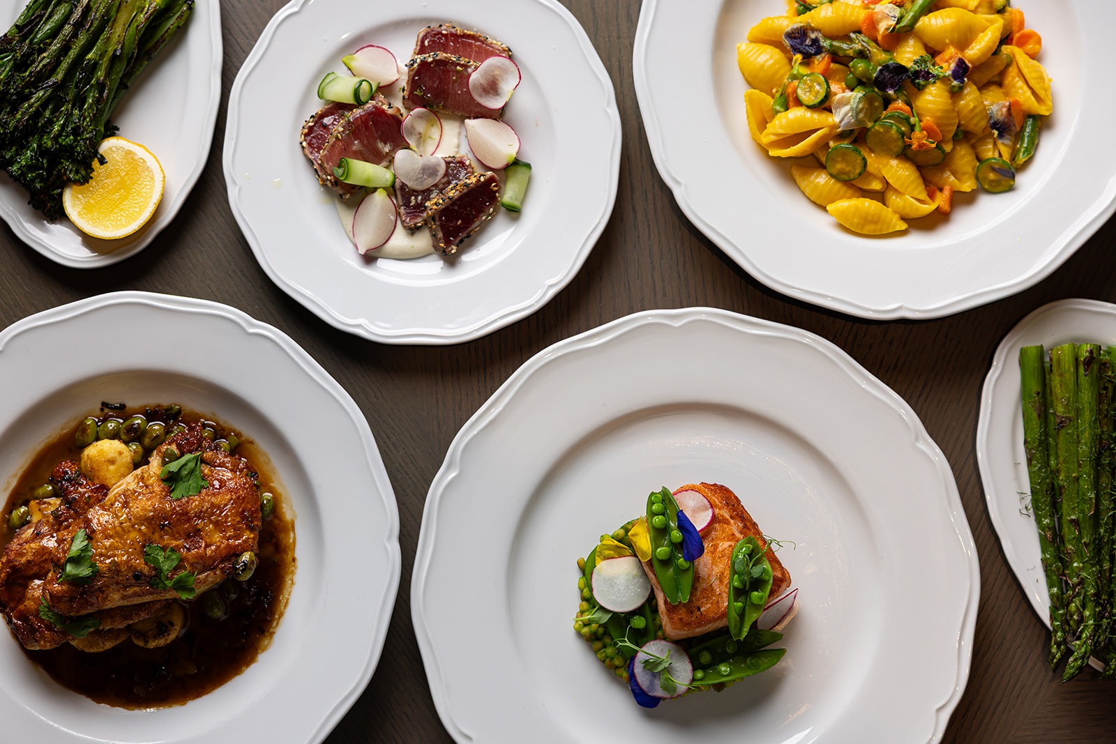 Gourmet dishes at a Boston Financial District steakhouse with seared tuna, salmon, pasta, chicken, and grilled asparagus.