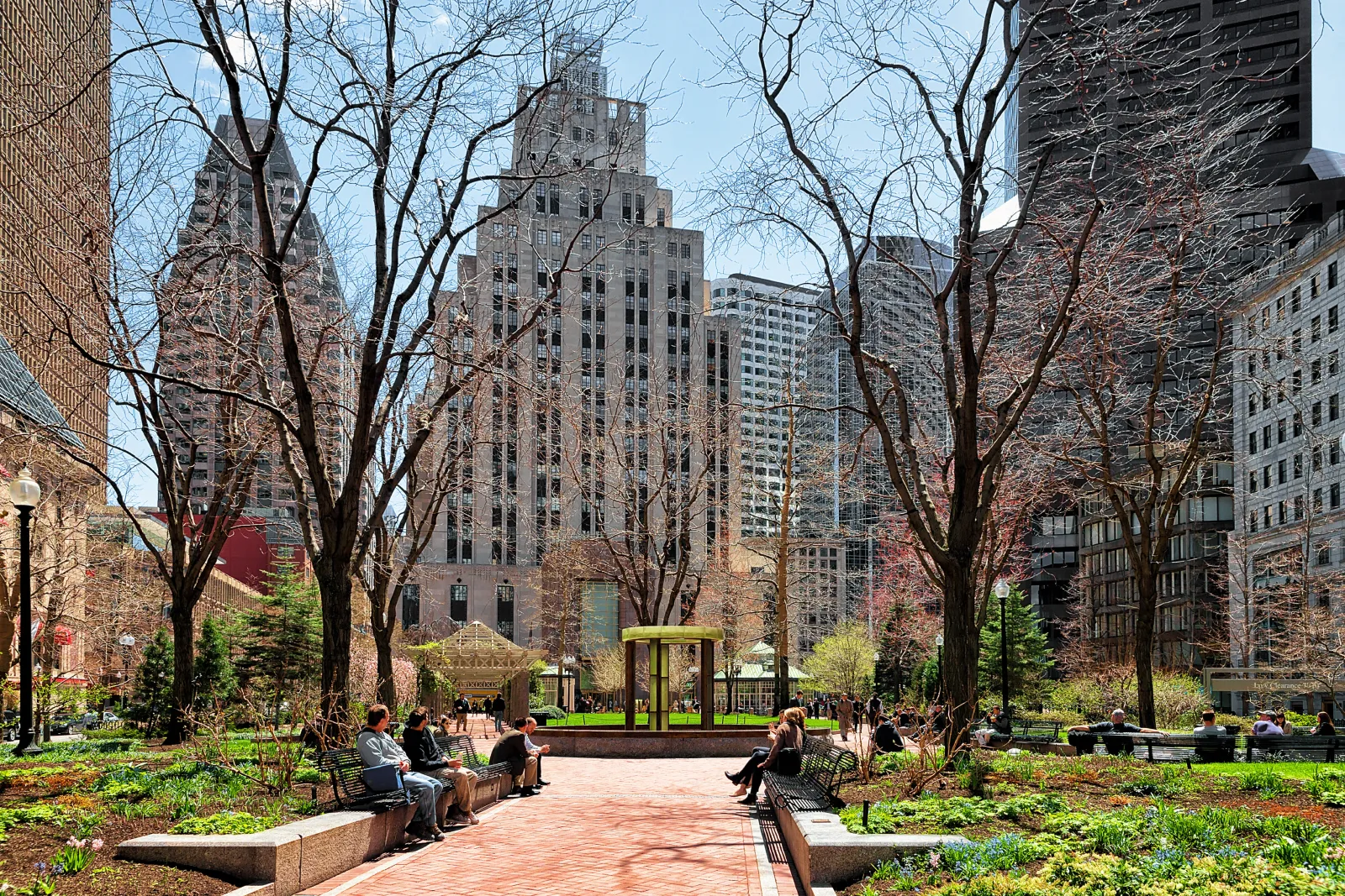 People relaxing in Post Office Square in Boston’s Financial District with tree-lined paths and office towers.