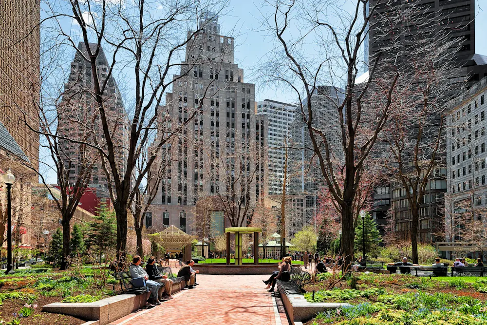 People relaxing in Post Office Square in Boston’s Financial District with tree-lined paths and office towers.