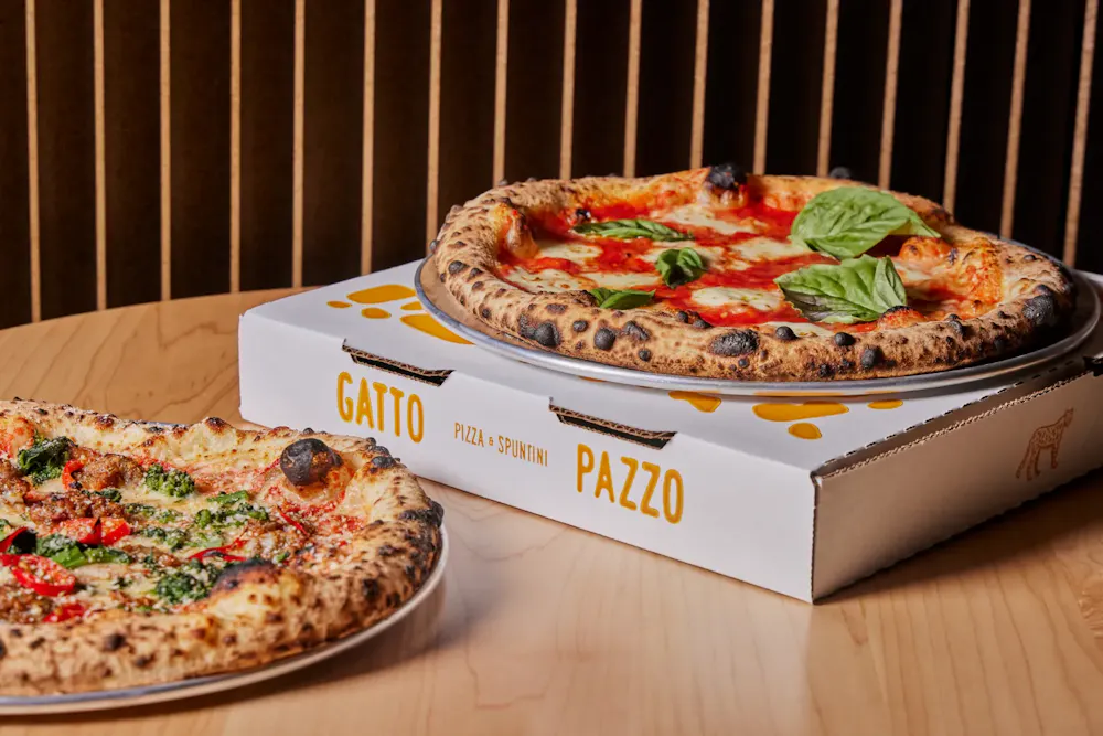 Two Neopolitan pizzas with charred crusts on a table, showcasing a great choice for lunch in Boston.