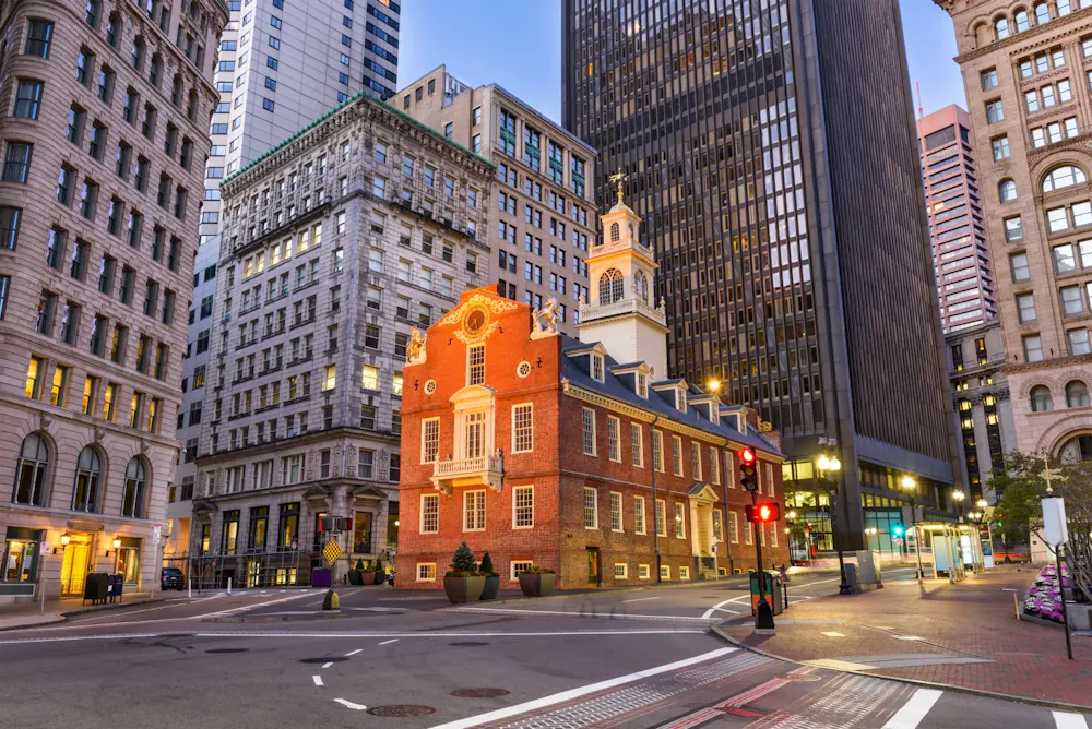 Old State House in Boston Financial District surrounded by modern skyscrapers at dusk in downtown Boston.