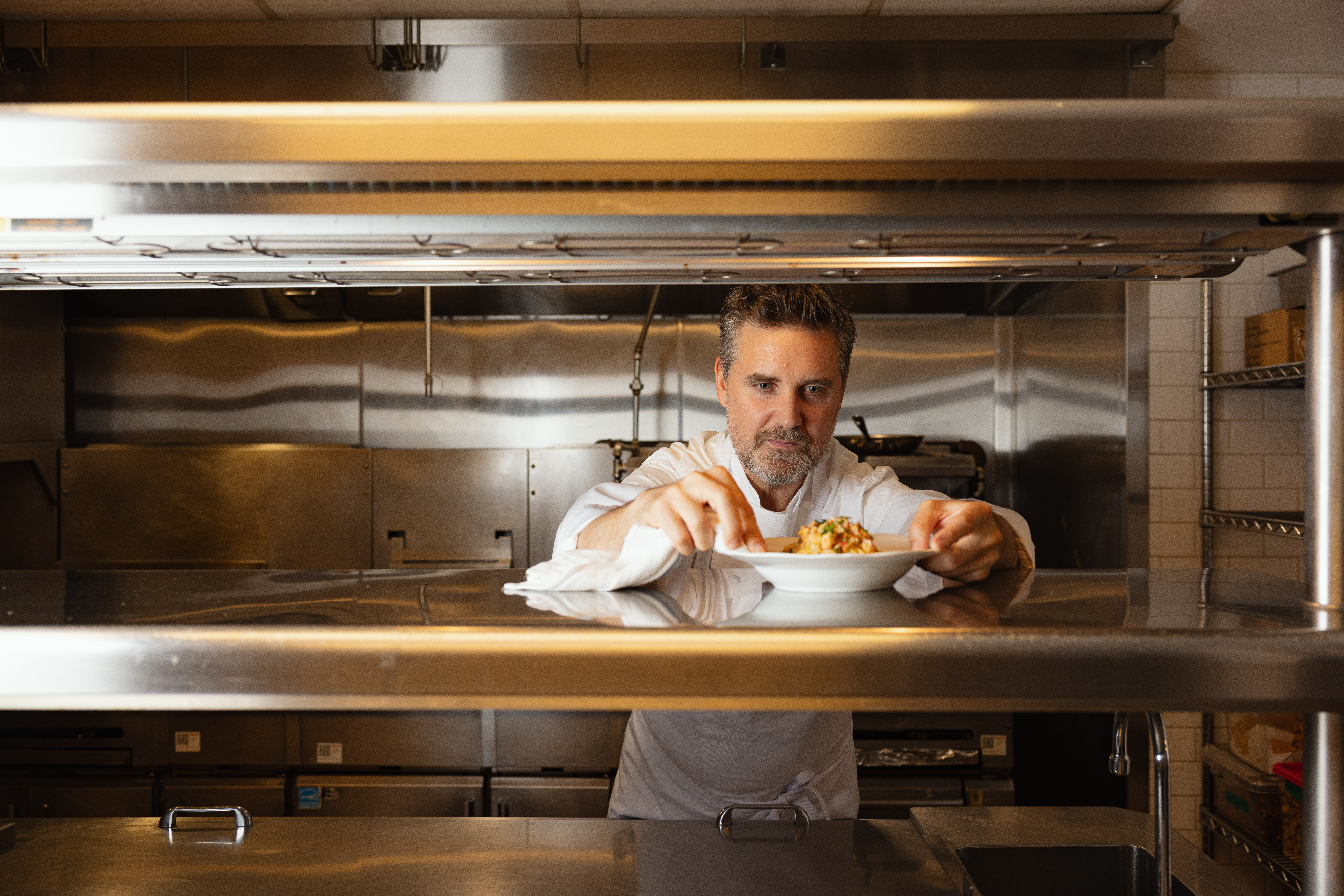 Chef John Fraser plating a dish in the kitchen at The Lineup, his Boston food hall.