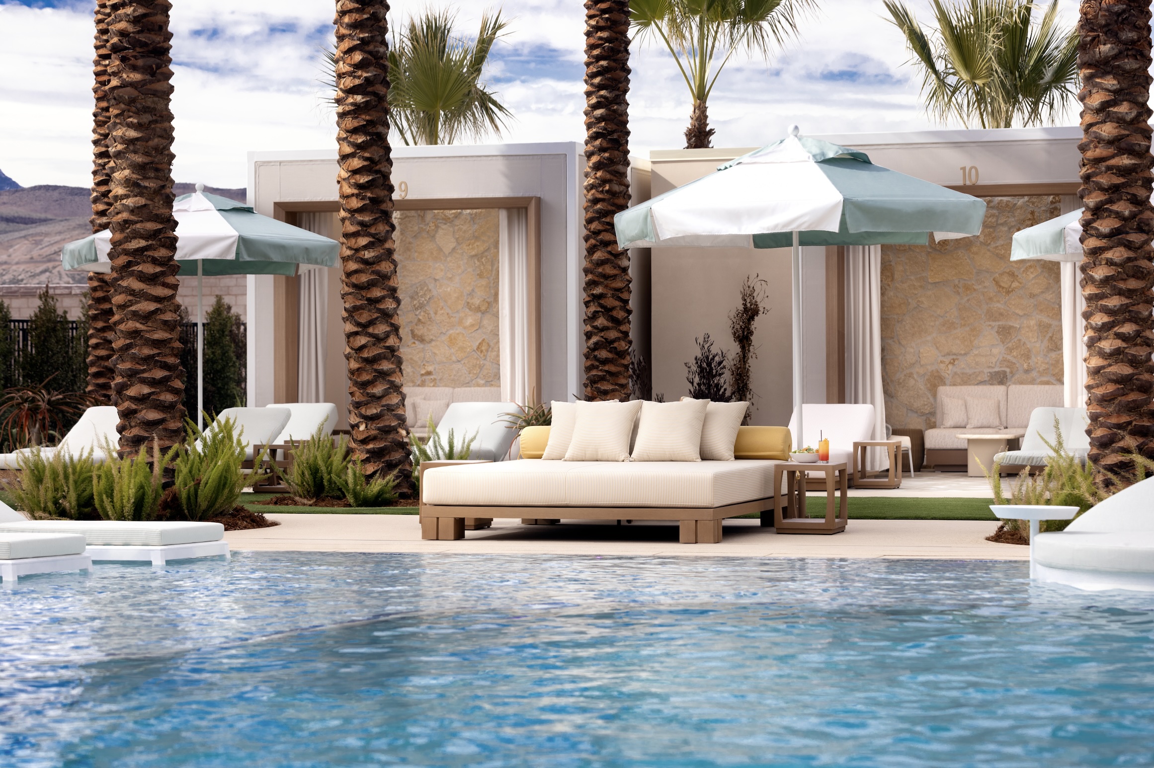 a daybed and a pool of water with an umbrella covering it