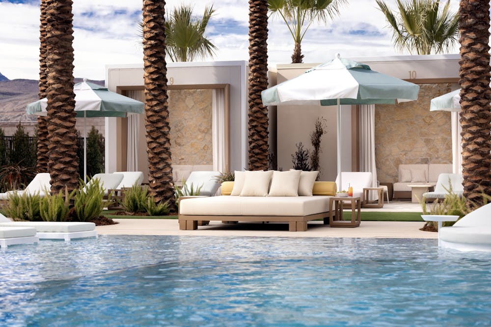 a daybed and a pool of water with an umbrella covering it