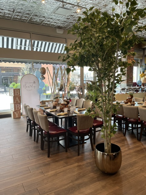 Tree in foreground, with tables set up for baby shower