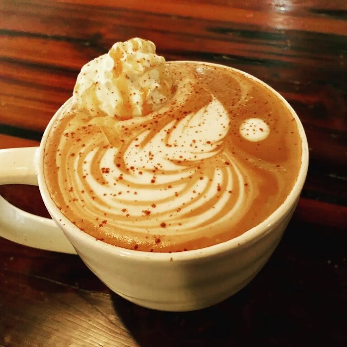a cup of coffee sitting on top of a wooden table