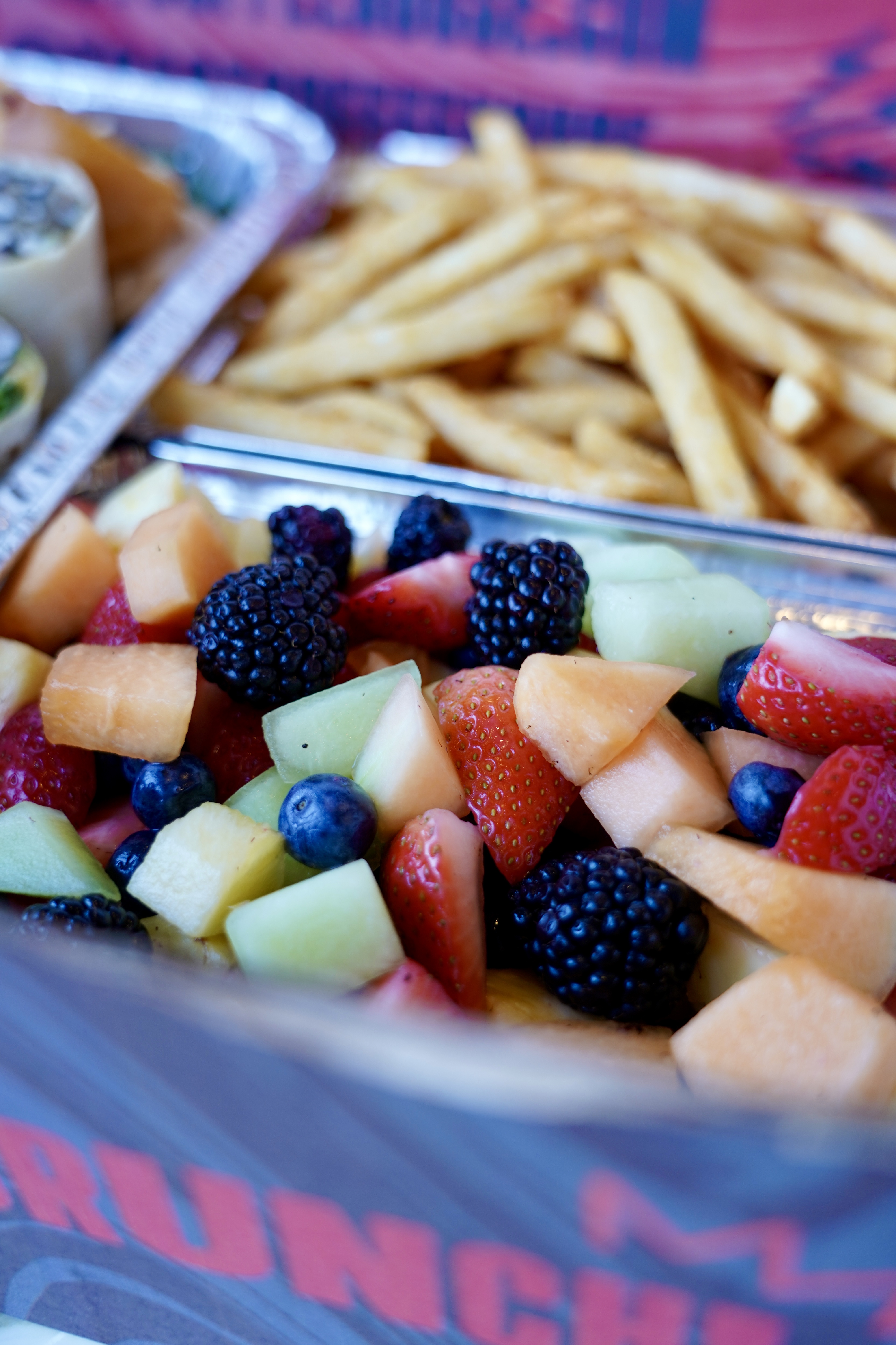 A close up image of fresh berries and melon, and french fries