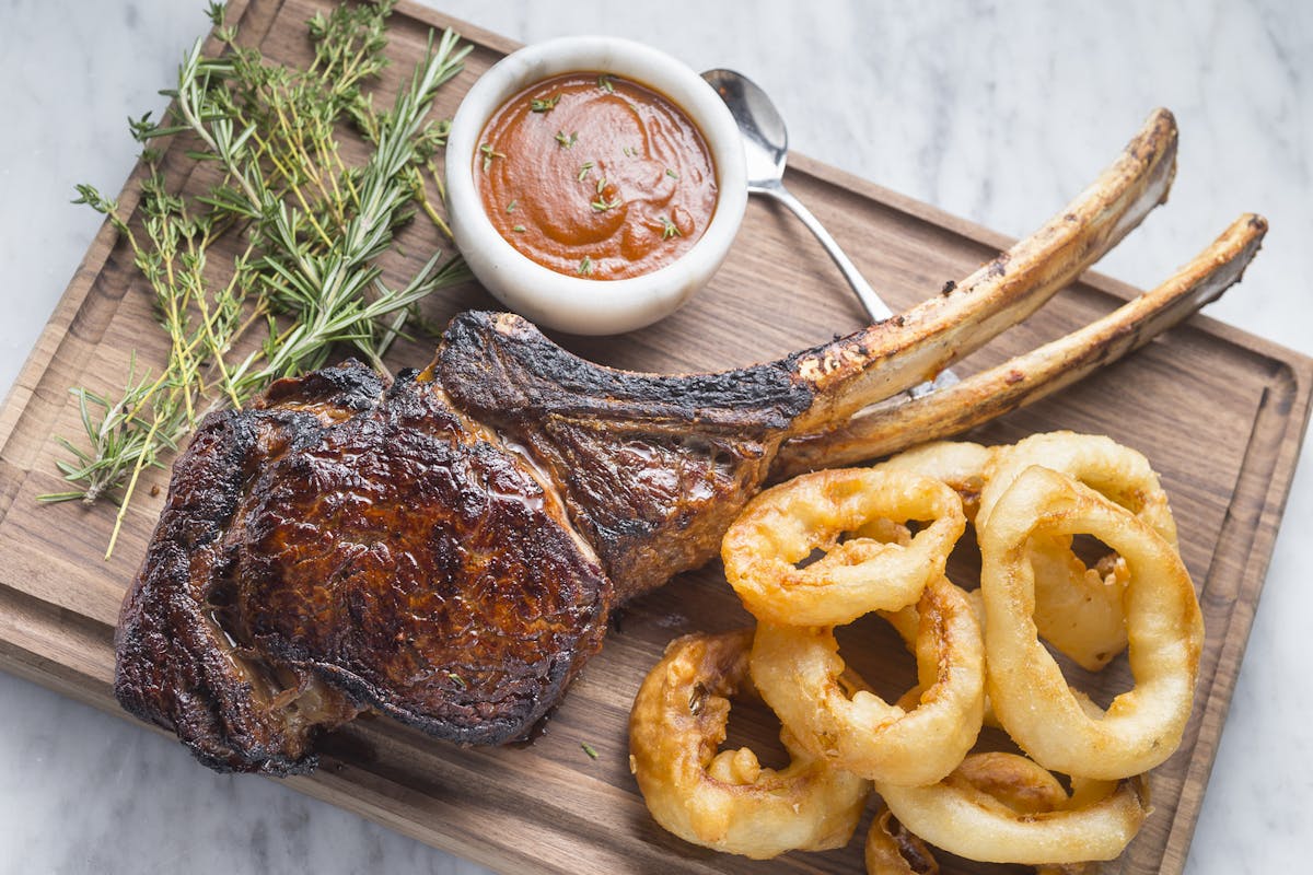long bone steak and onion rings on a table