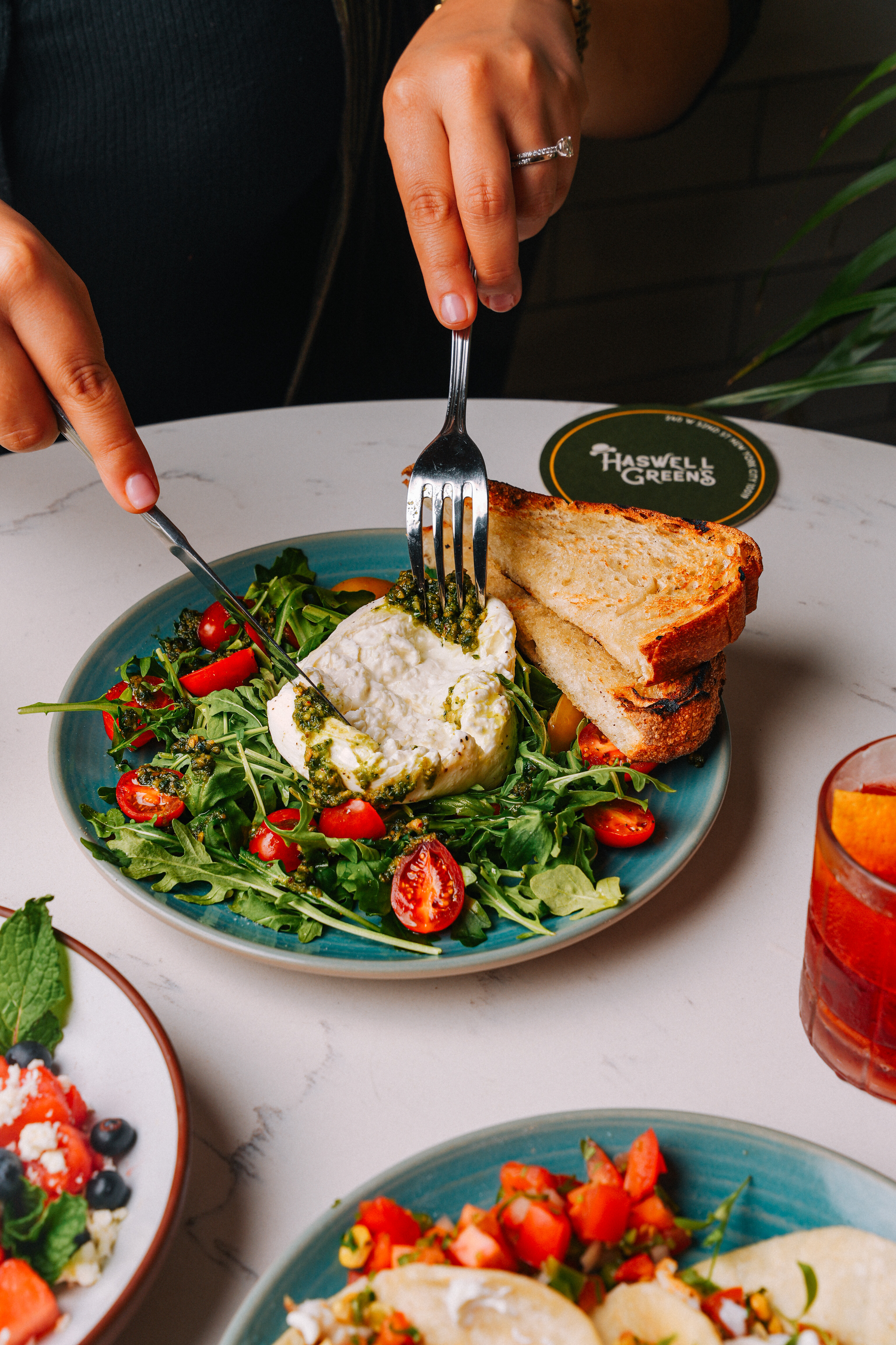 a person holding a plate of food on a table