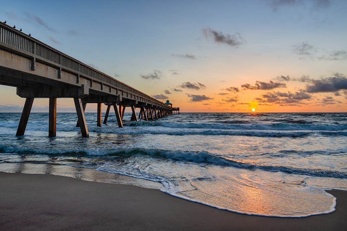 a beach with a pier in front of a body of water