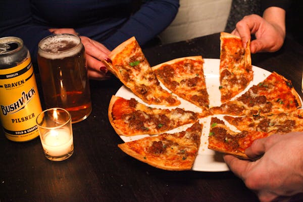 a person holding a slice of pizza sitting on top of a table
