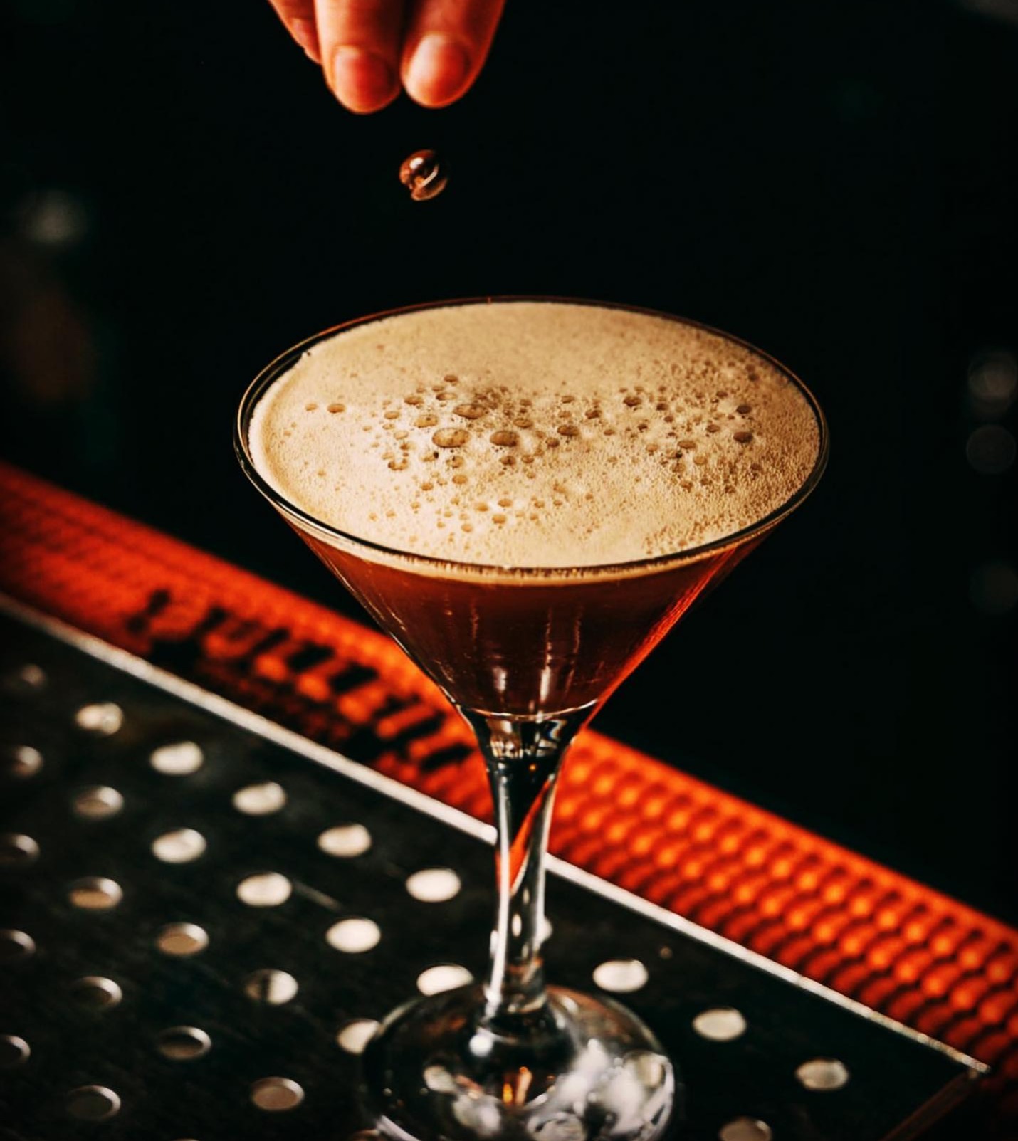a hand holding a small brown object over a glass of liquid