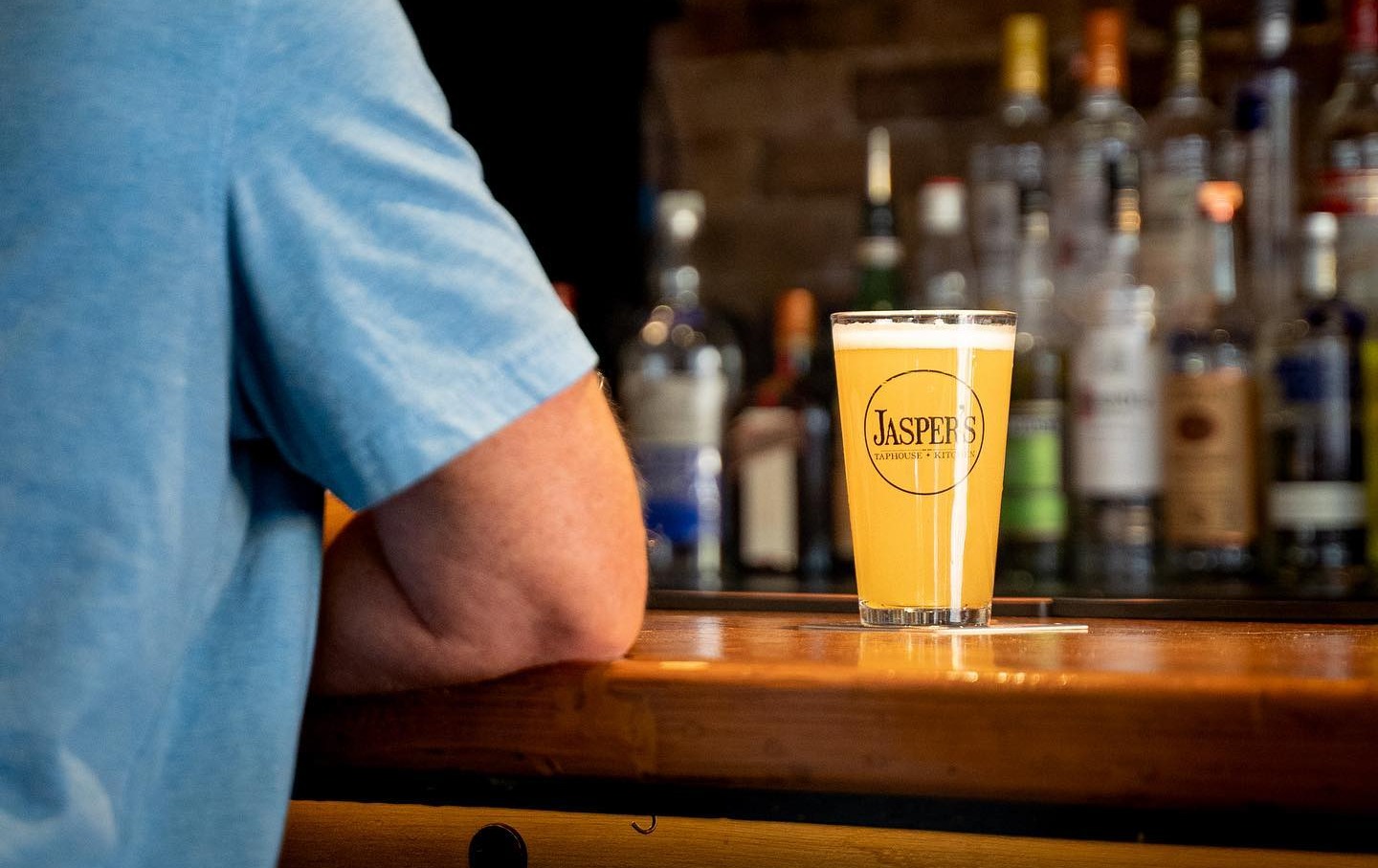 a person sitting at a bar with a glass of beer