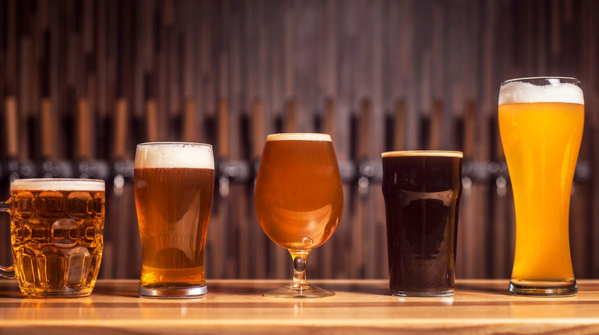a glass of beer on a table with wine glasses