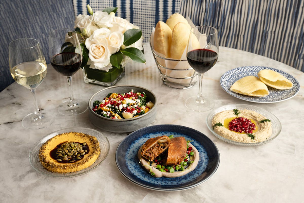 a mediterranean spread of dips and mezzes on top of a table
