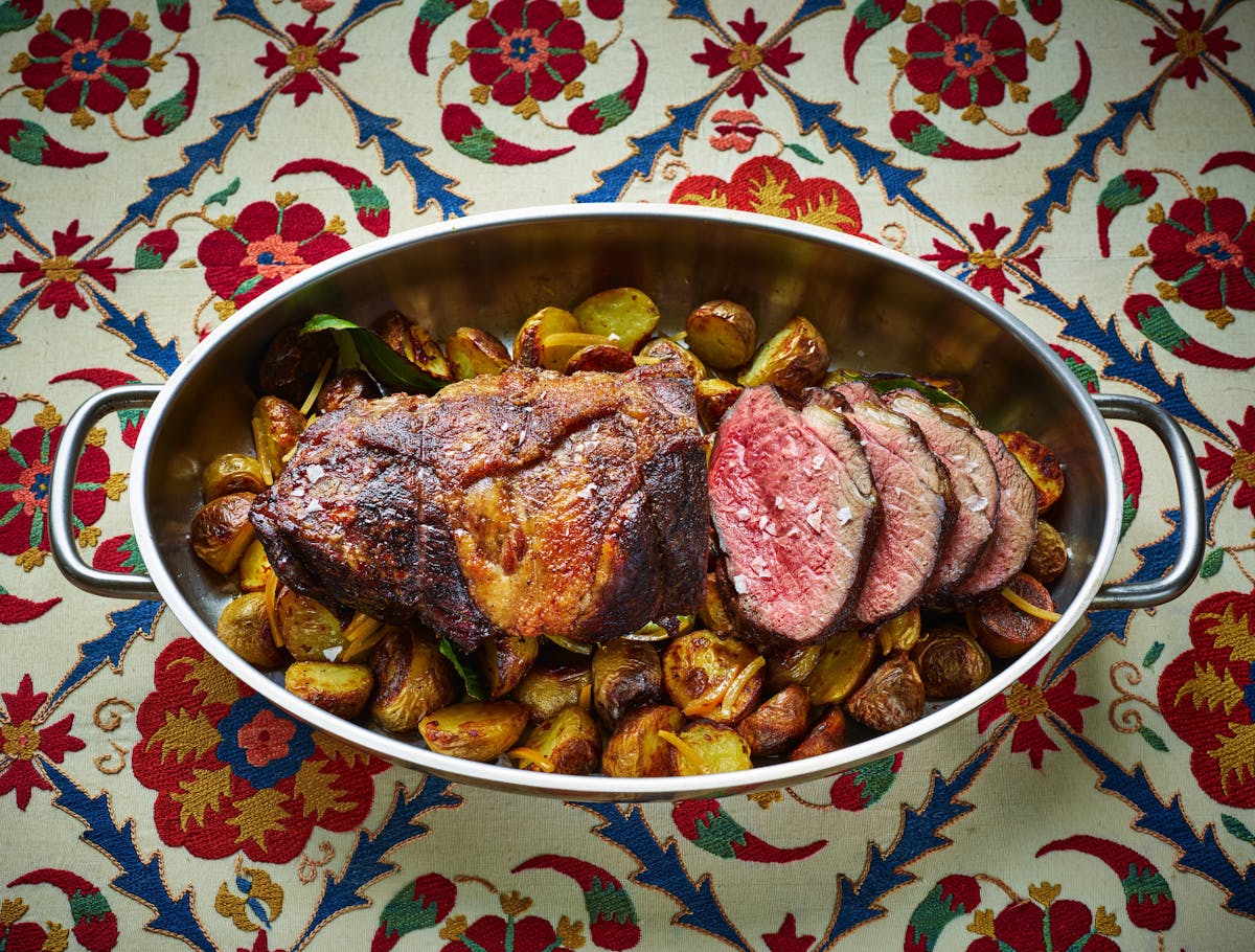 a roasted lamb leg over potatoes