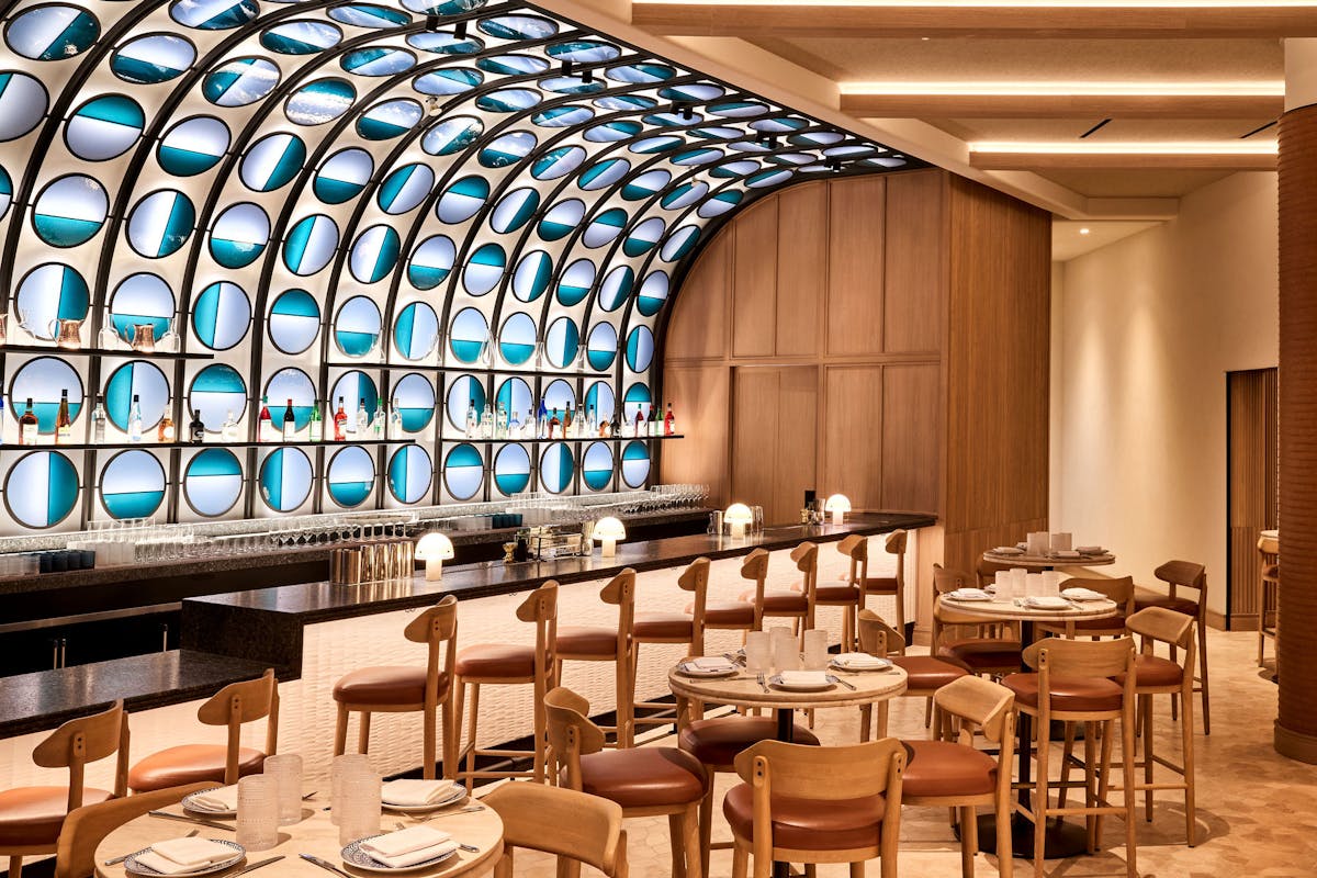 a dining room with bar seating with a wall of blue stained glass.