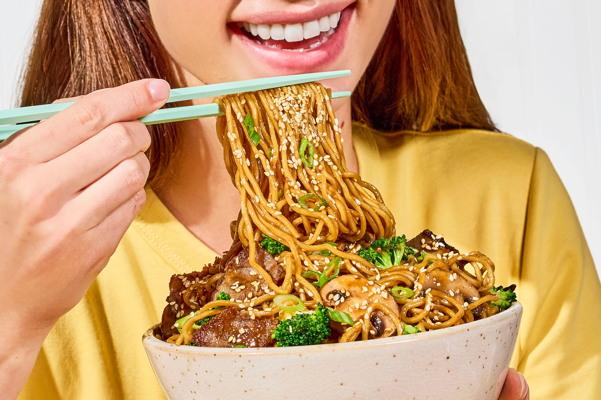 a woman eating noodles with chopsticks