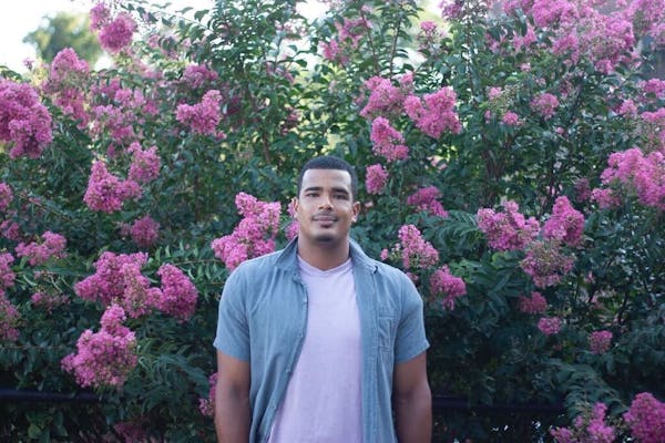 a person standing in front of a purple flower