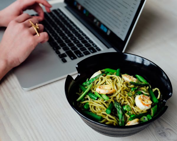 a person working on a mac next to salad