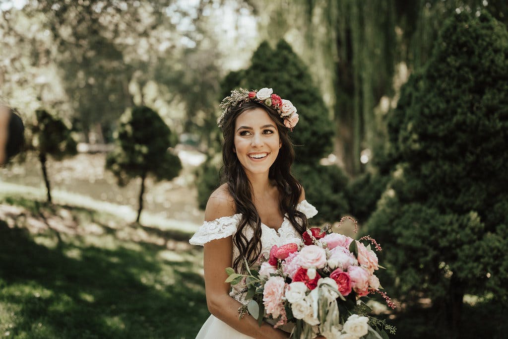 a bride with a bouquet of flowers smiling at the camera