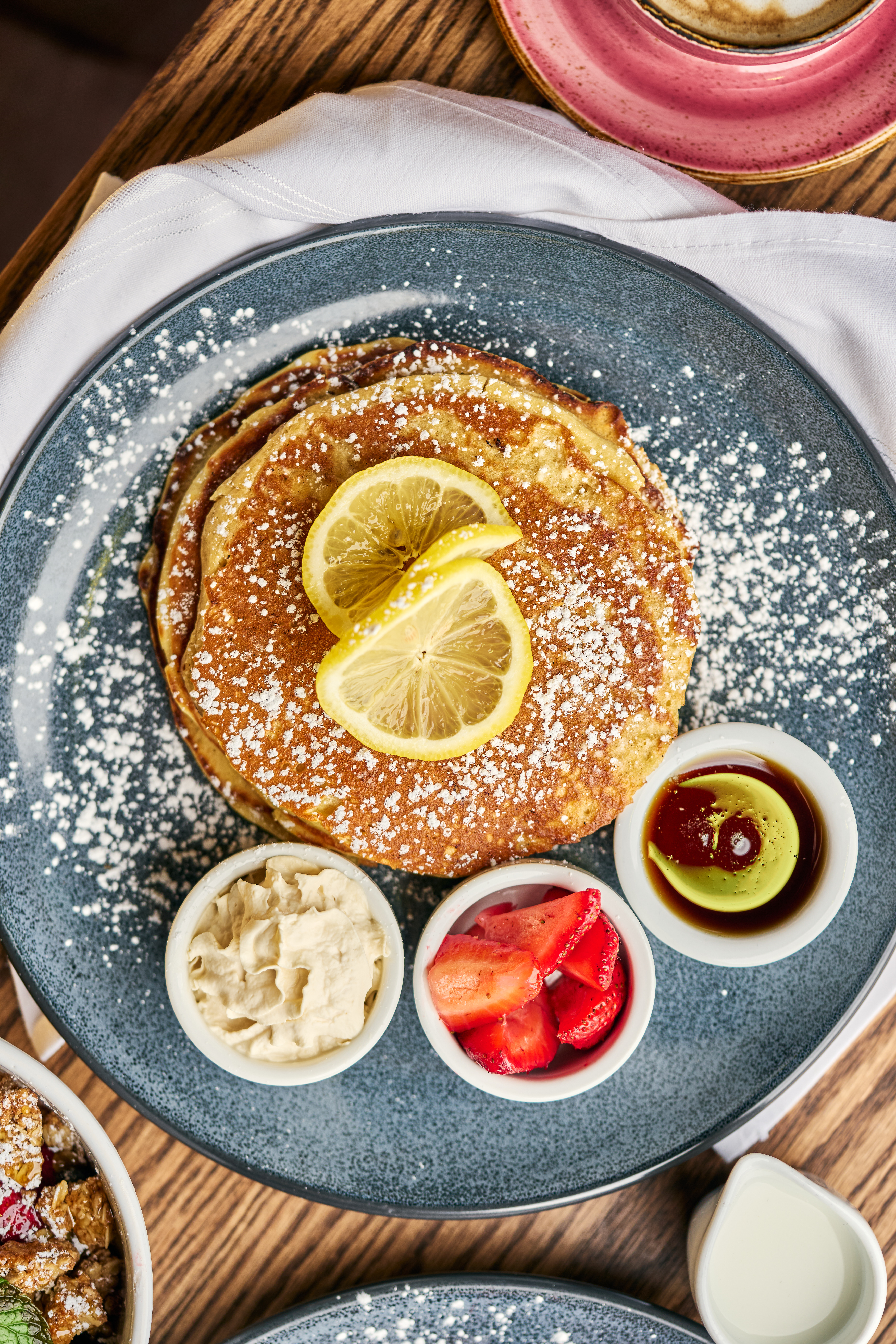 a plate of pancakes with fruit and sauces