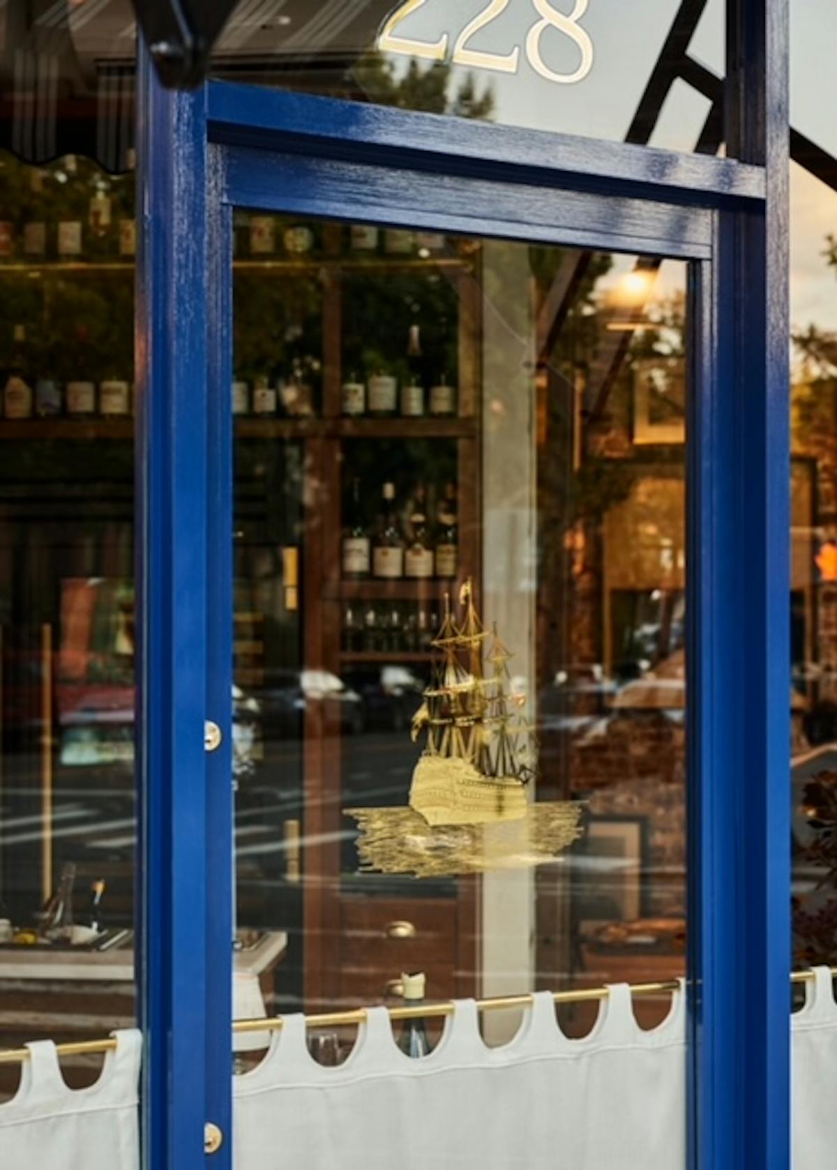 a glass with a blue sign in front of a store window