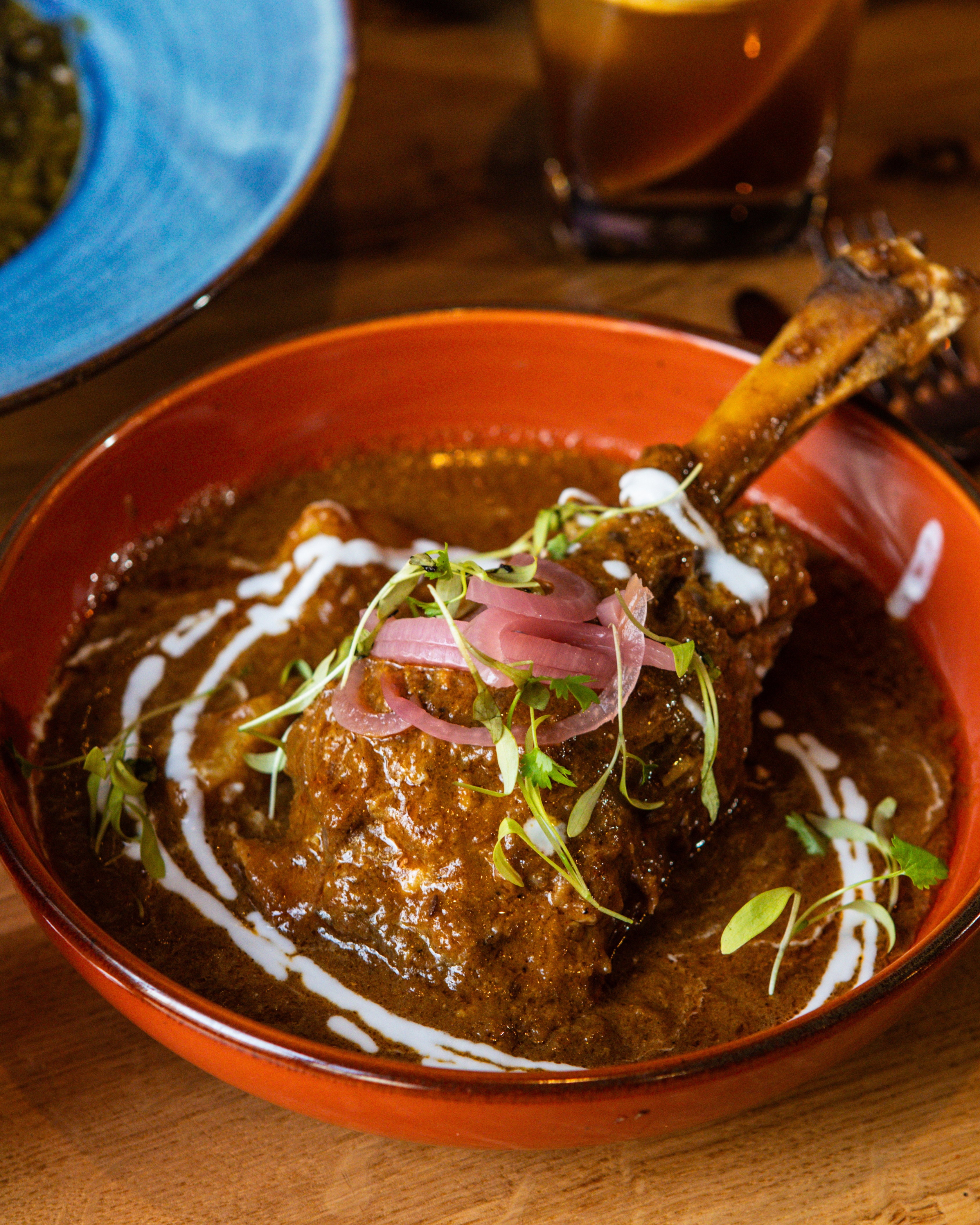 Braised lamb shank served in a spiced sauce with yogurt drizzle