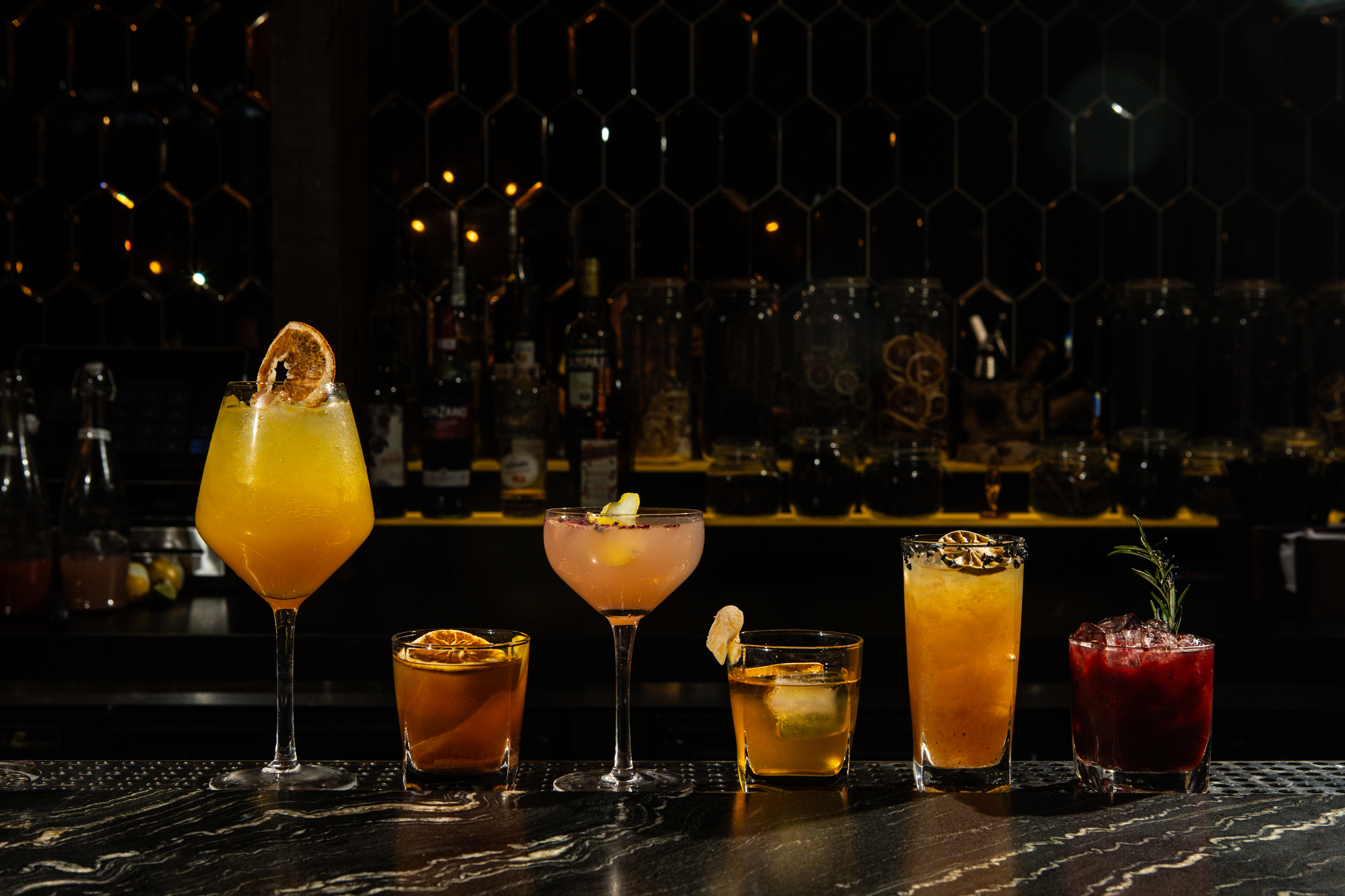 Bartenders lining up freshly made craft cocktails along the bar at KAMA