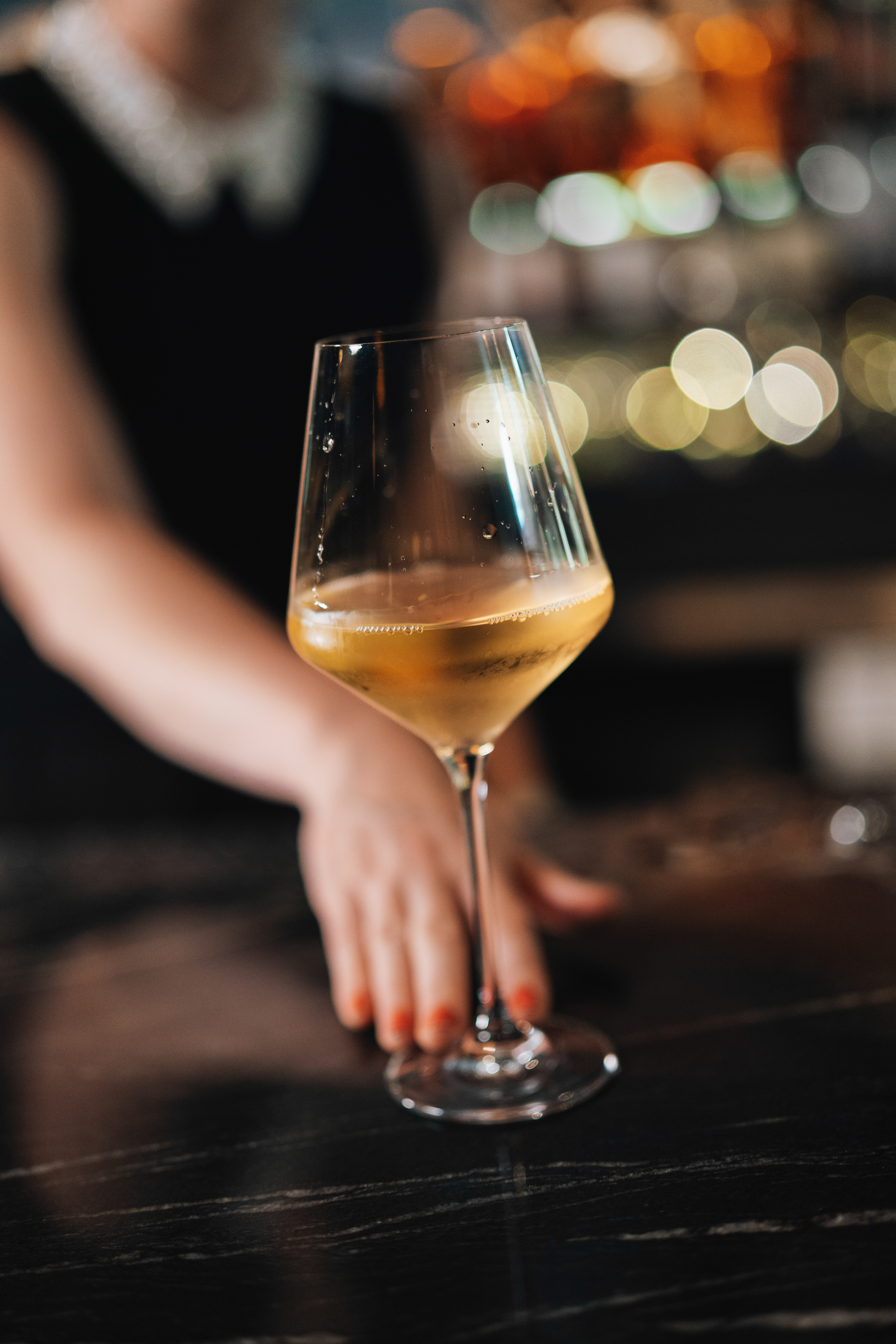 A glass of wine resting on a bar top, warm ambient lighting at KAMA