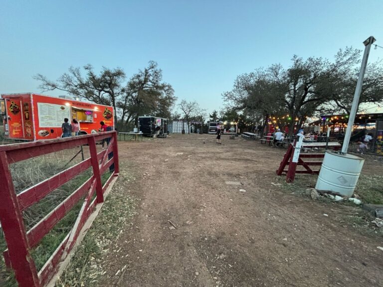 a train is parked on the side of a dirt field