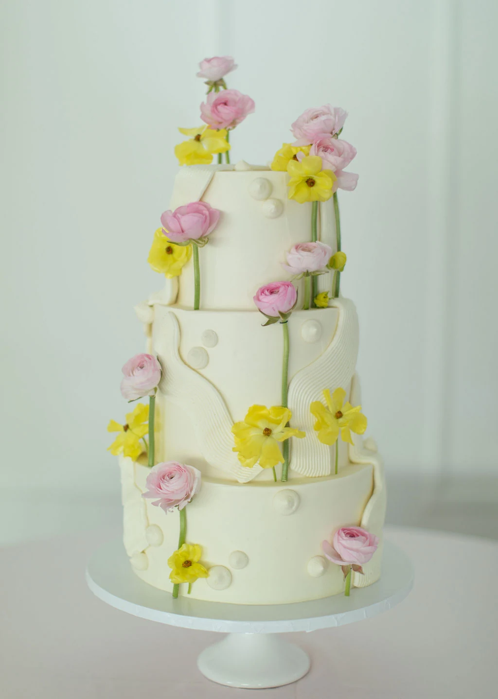 Three-tier white cake decorated with pink and yellow flowers