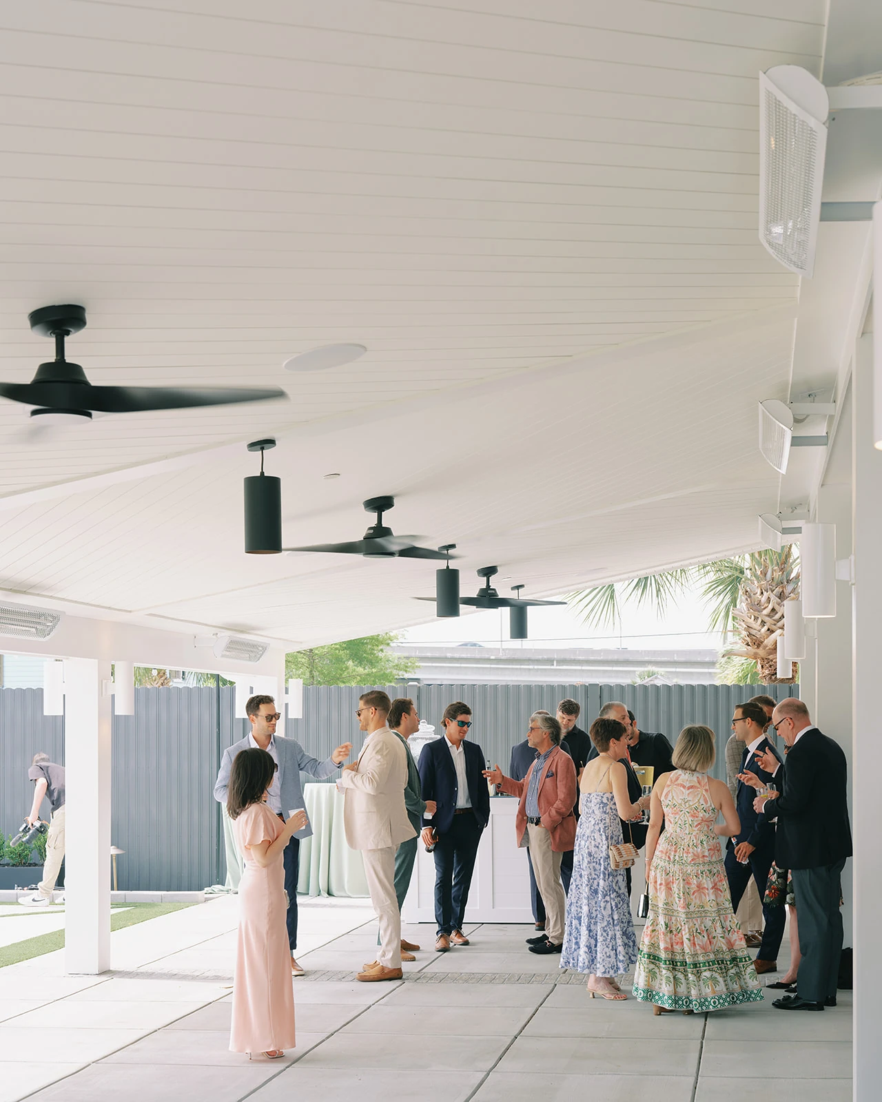 Wedding guests enjoying cocktail hour beneath the covered roof and ceiling fans at The Waverly