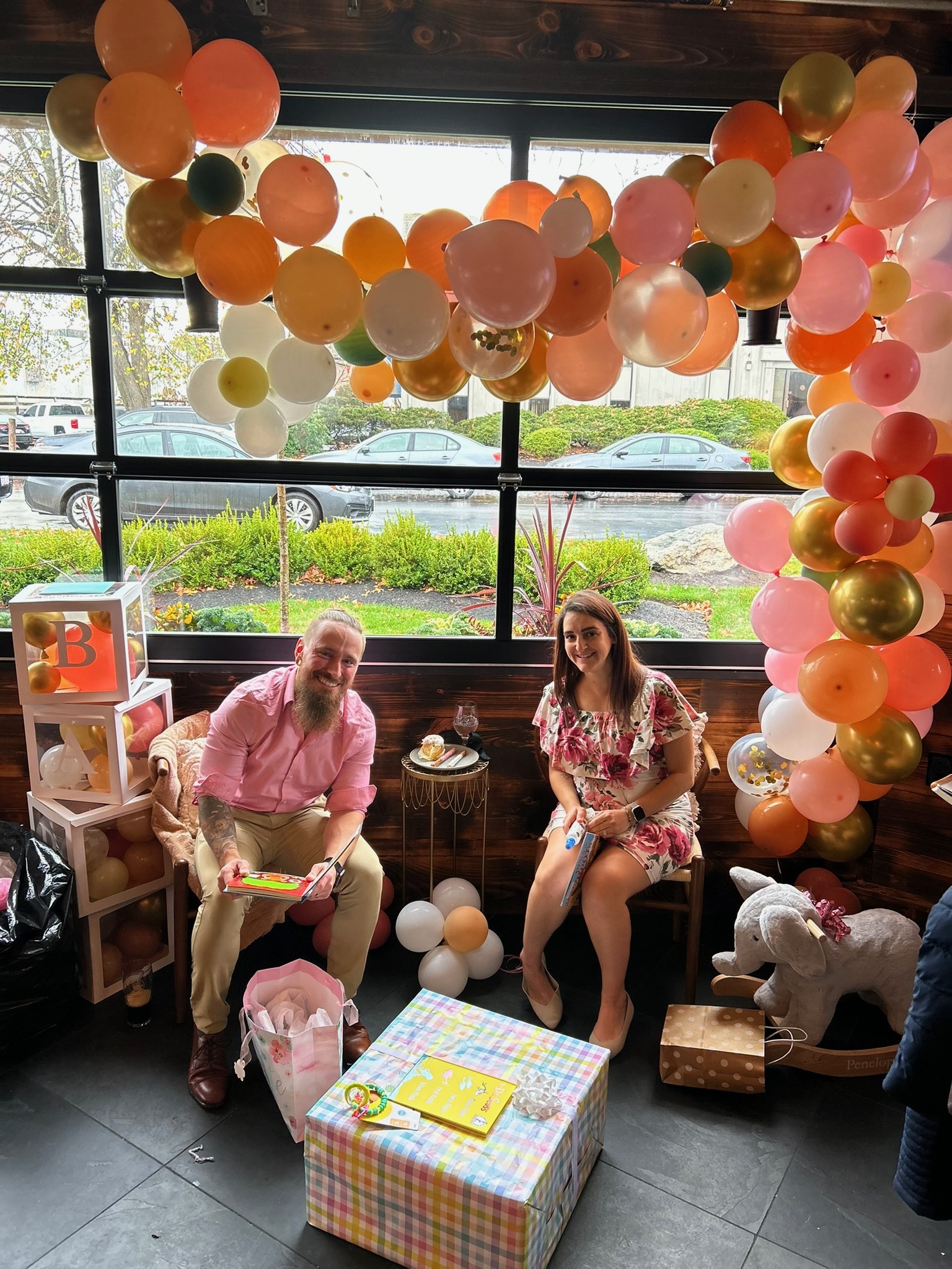 a man and woman sitting in chairs with balloons in the background
