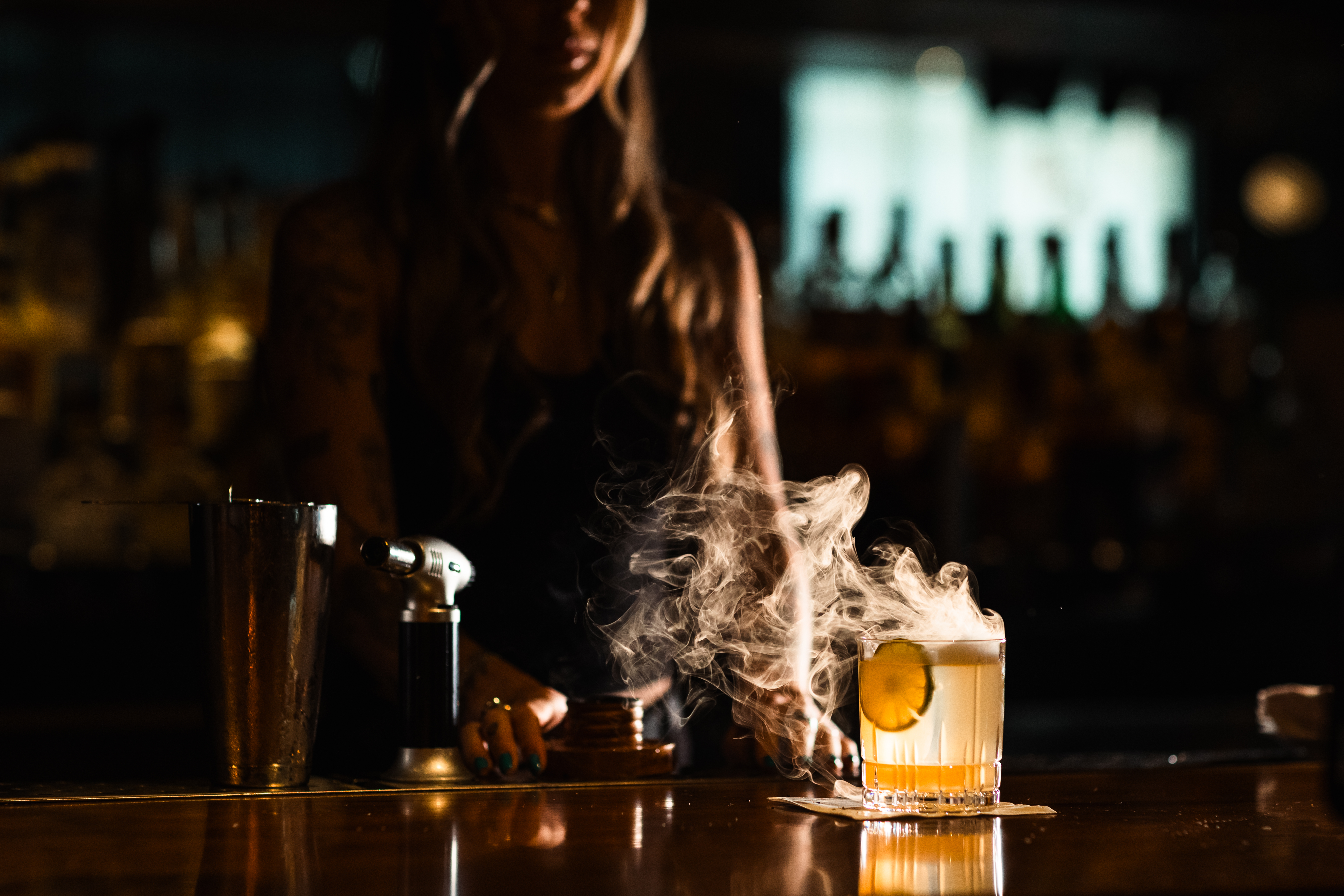 a woman standing behind a glass of liquid