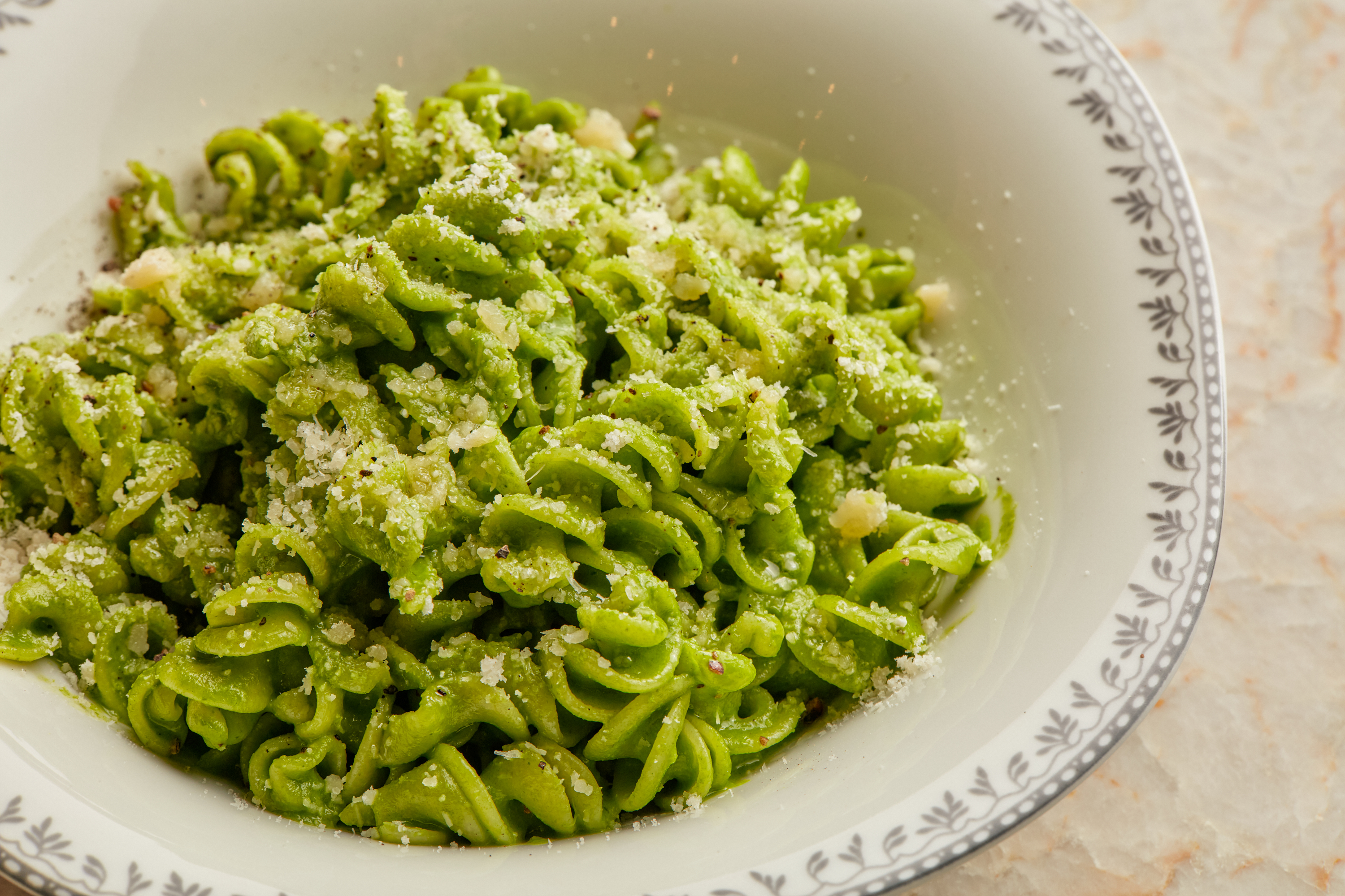 a bowl of noodles with sauce and broccoli on a plate