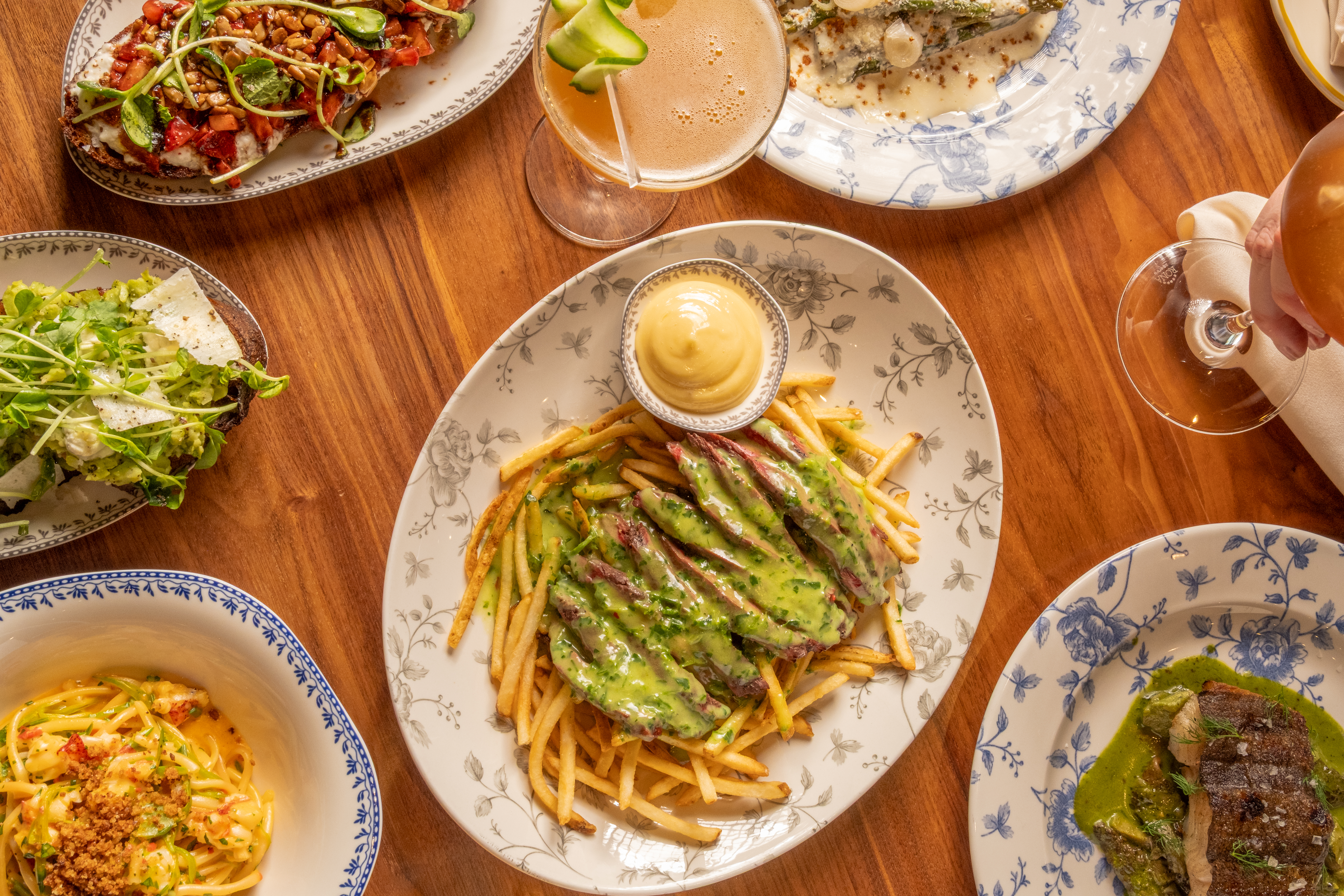 a group of dishes including french fries with dip and a green sauce available at bar tutto in Chicago's west loop