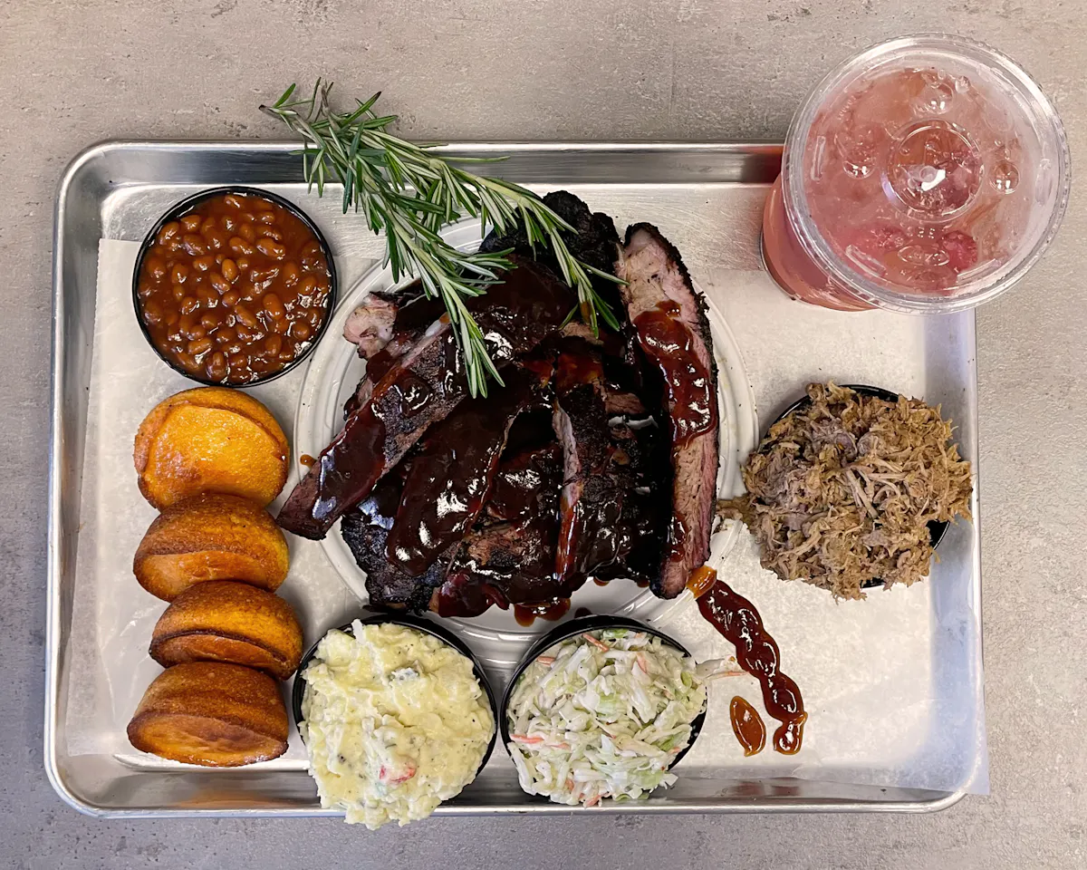 a tray of ribs with sides and a drink