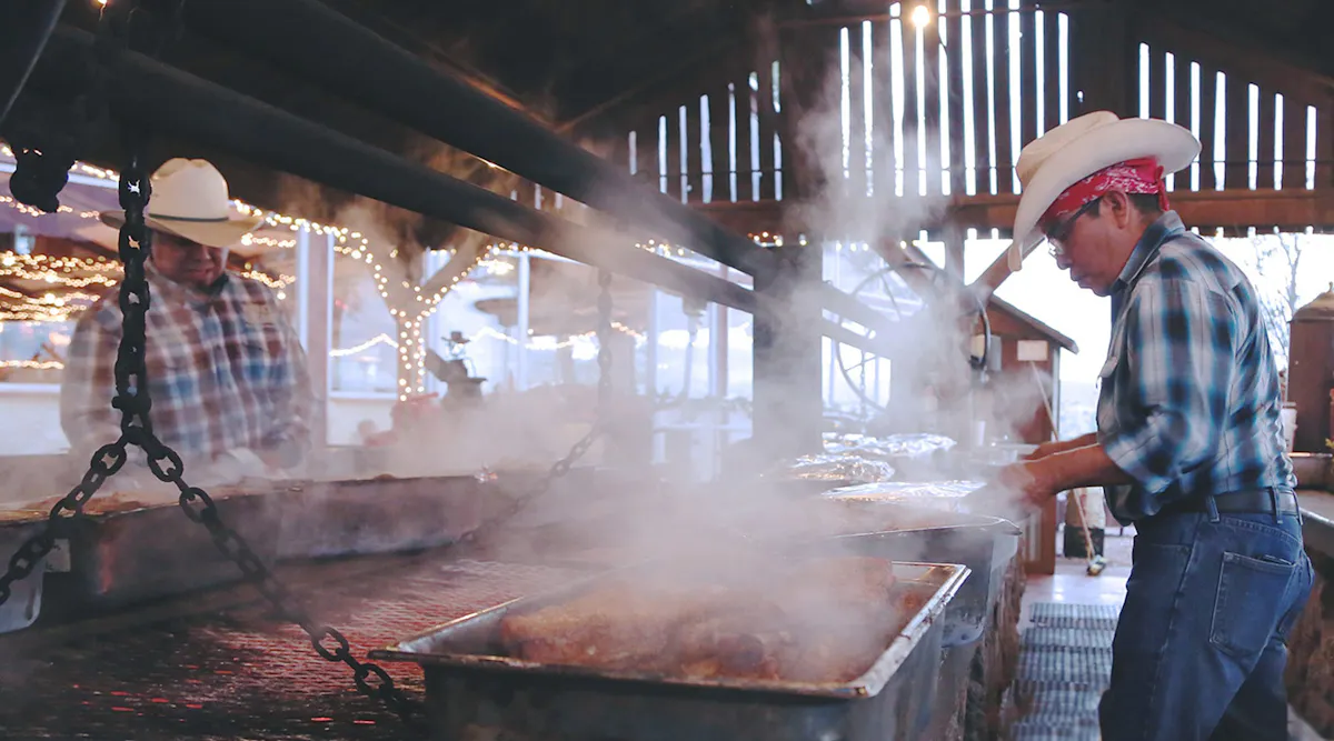 a man cooking hot dogs on a grill