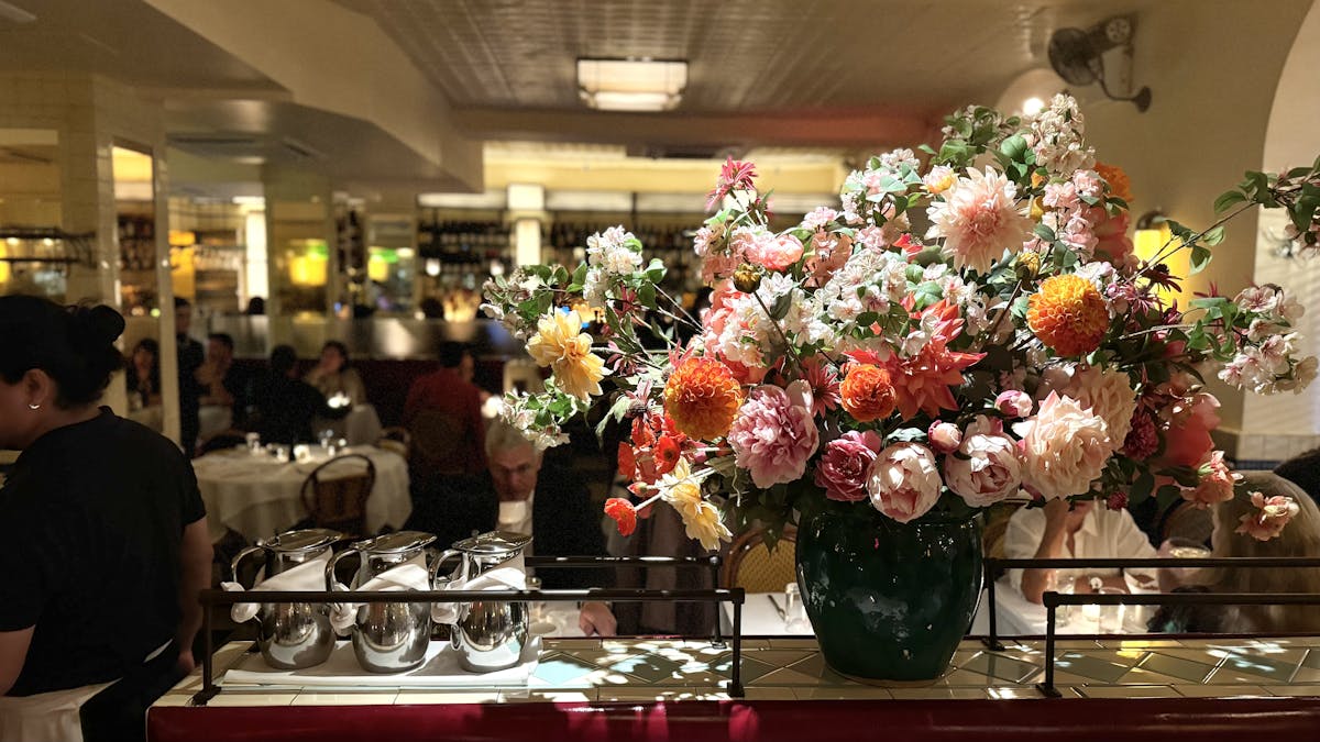 a group of people sitting at a table with a vase of flowers