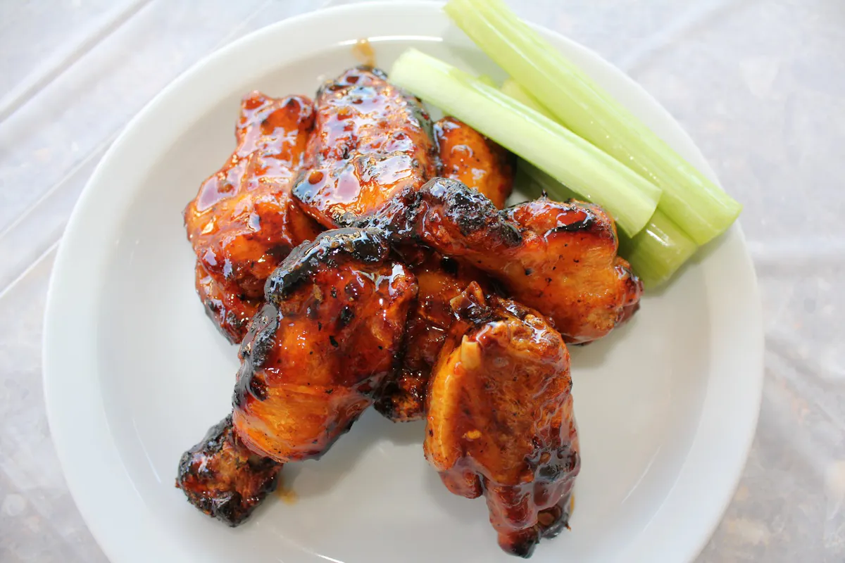 a white plate with chicken wings and celery 