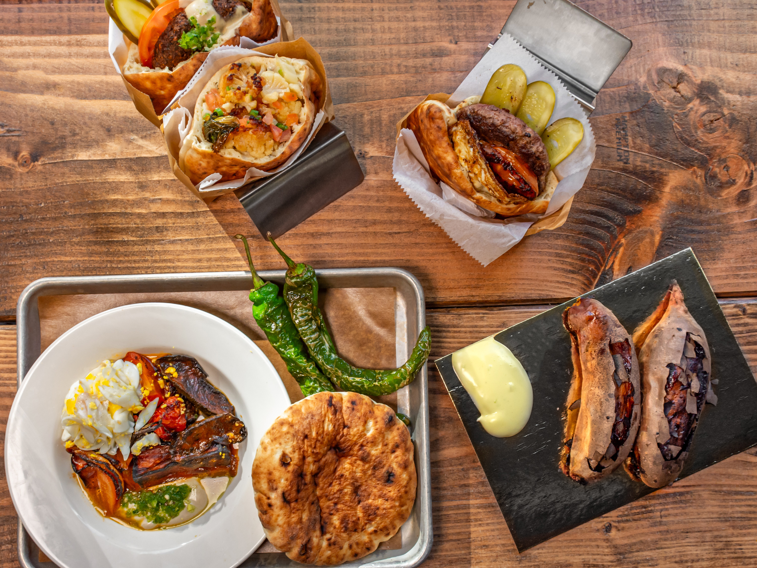 a plate of hummus with topping and three pita sandwiches with a sweet potato on the side