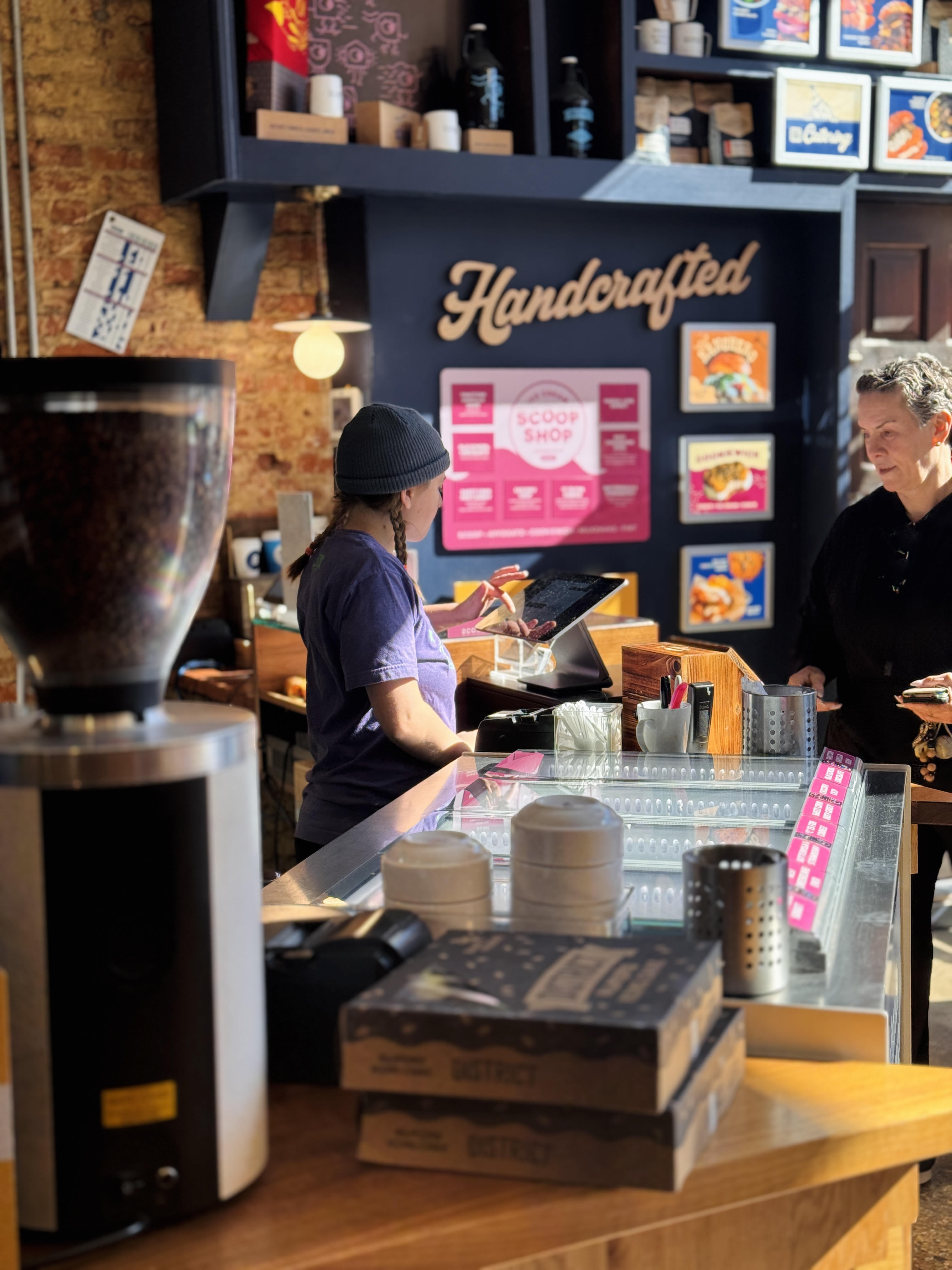 a woman standing behind a counter in a bakery