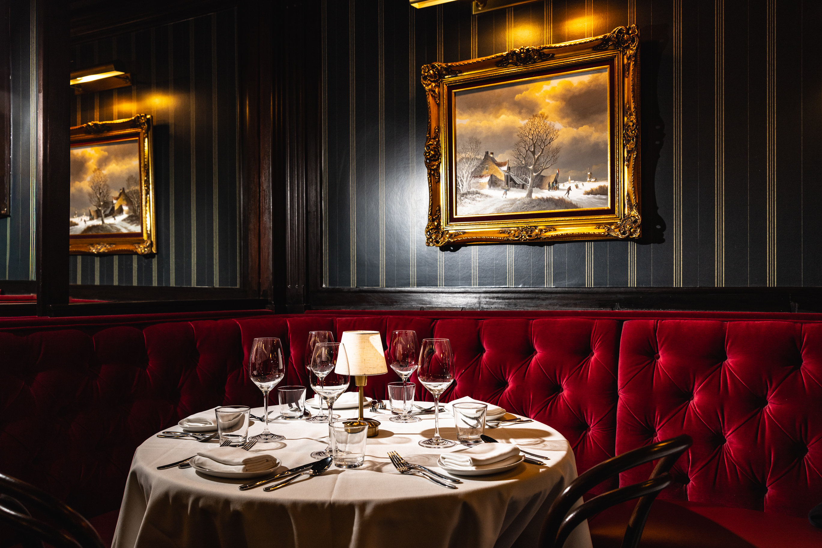 a table with wine glasses and a painting on the wall