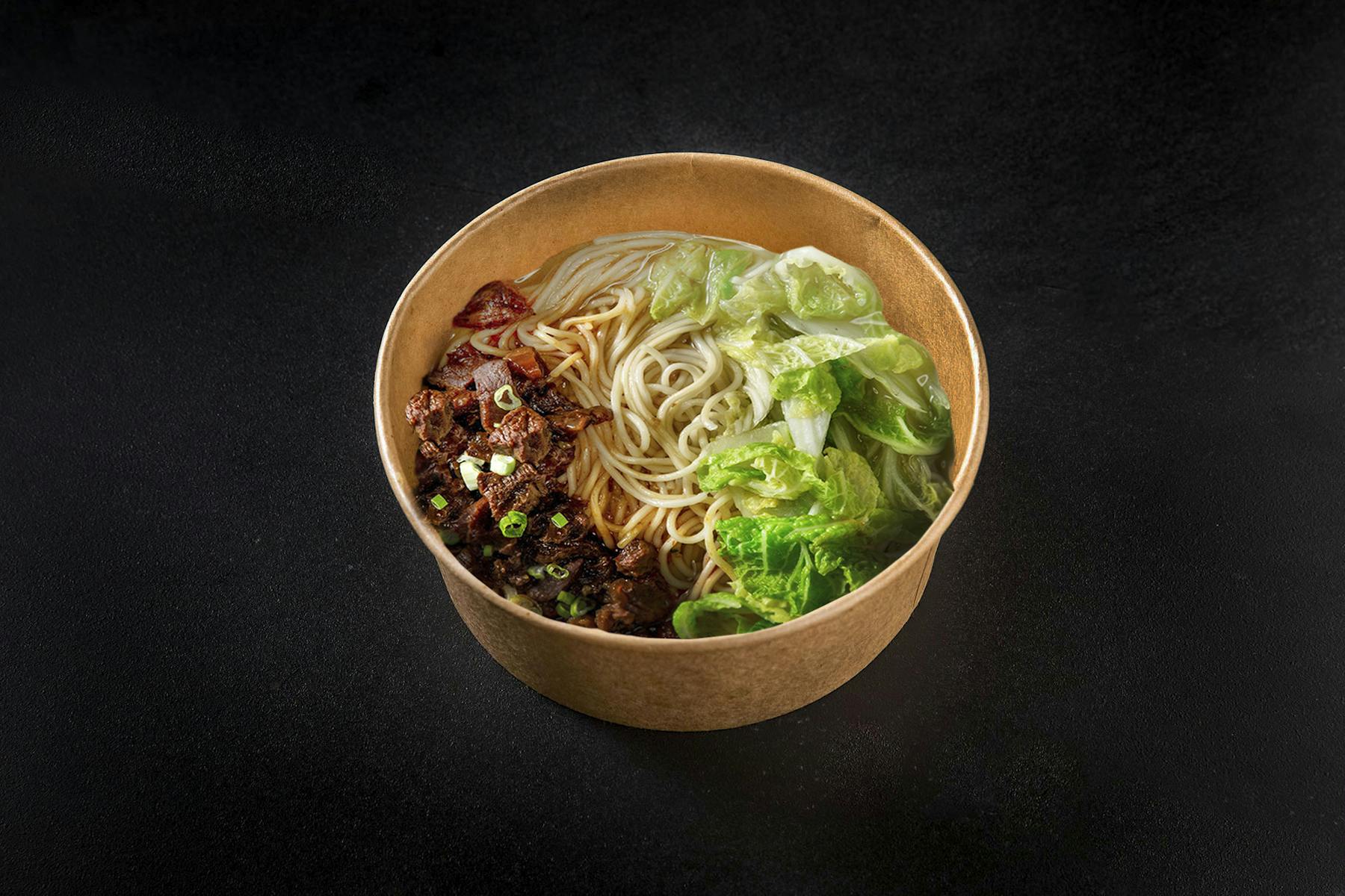 a bowl of noodles, meat, and veggies
