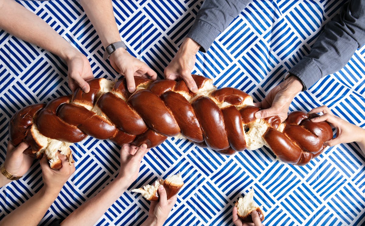 hands pulling apart challah bread