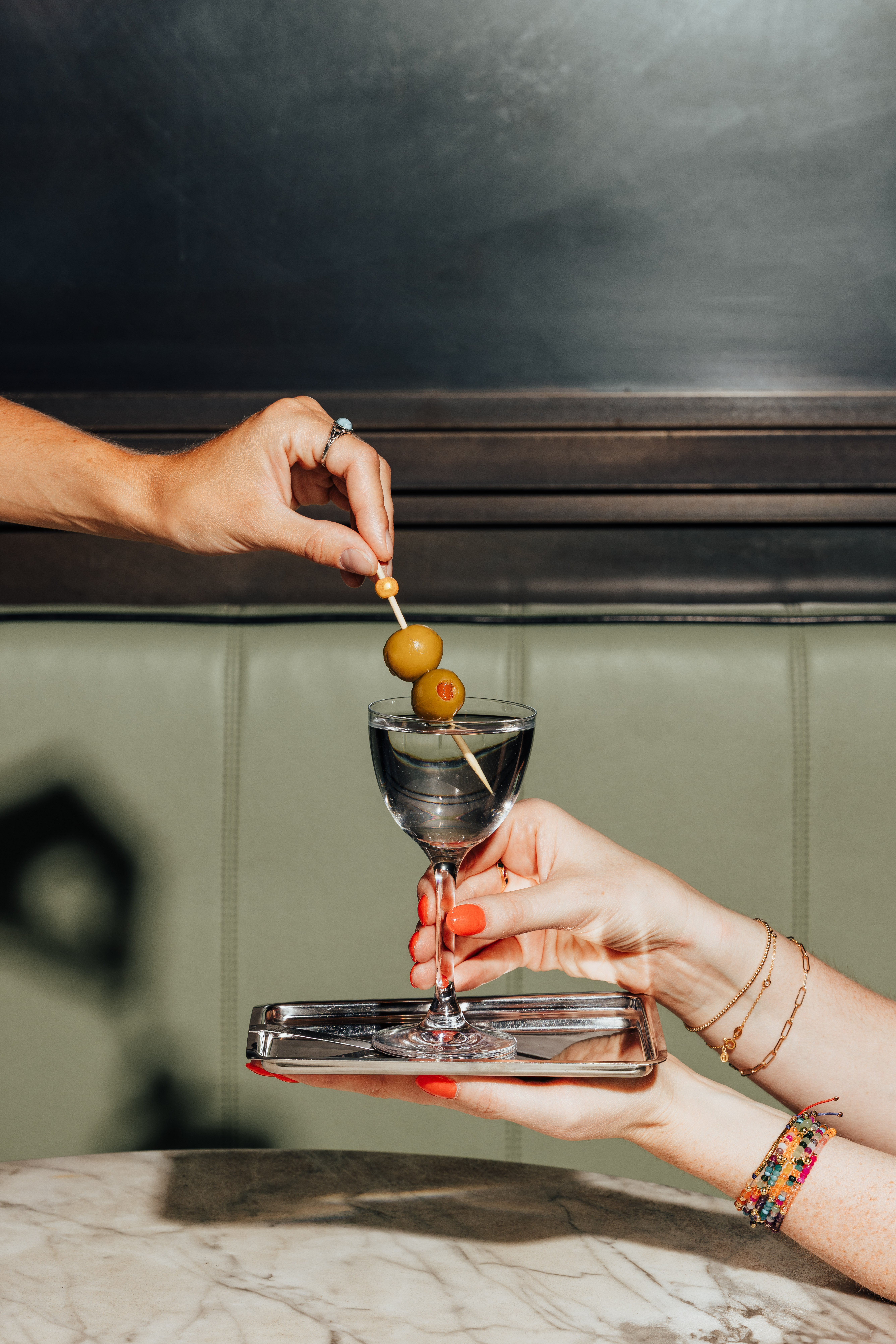 a person holding a glass with a drink and olives