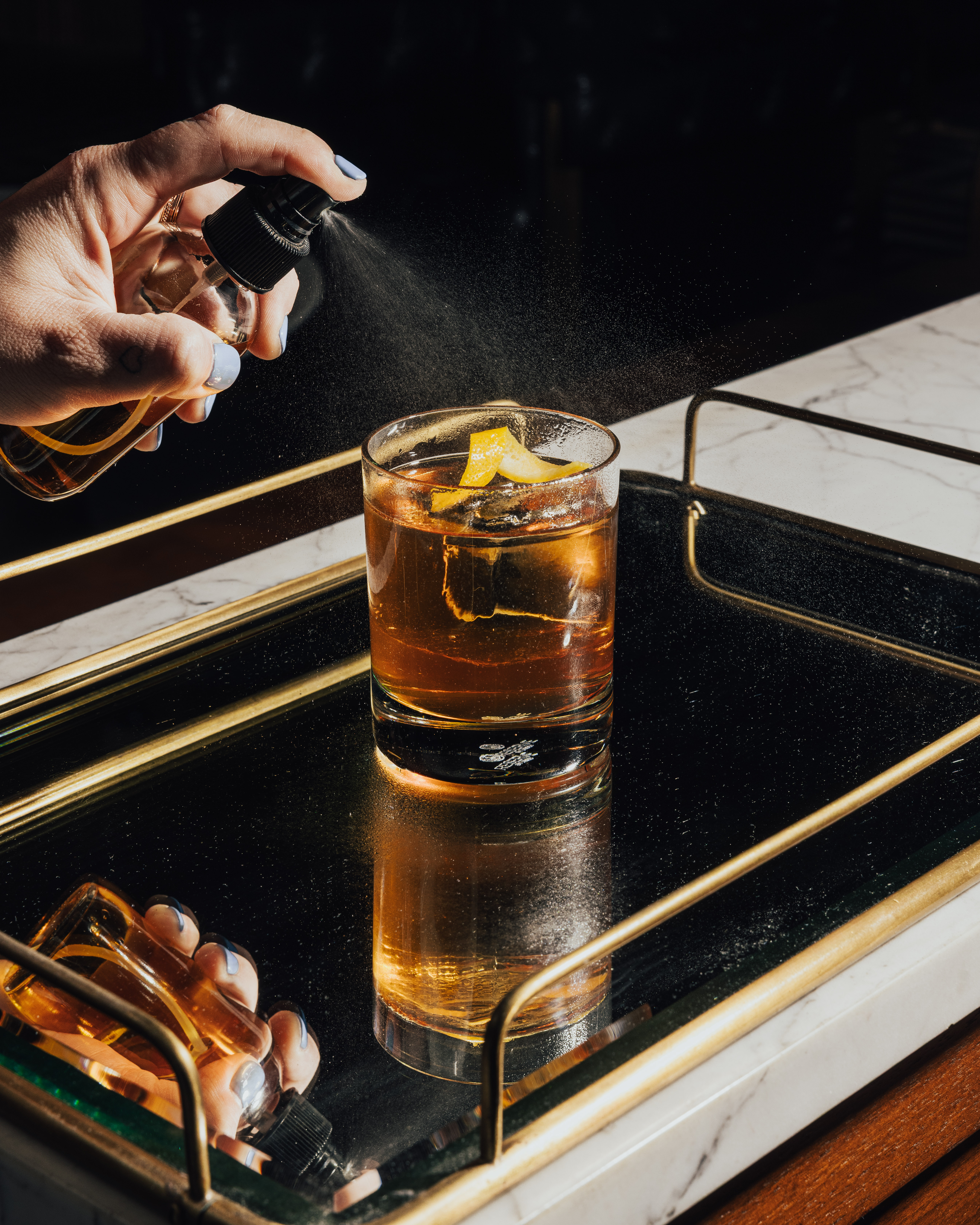 a person spraying a drink into a glass