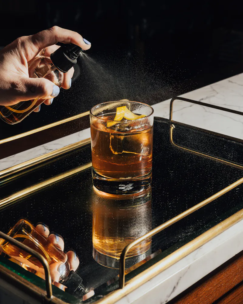 a person spraying a drink into a glass